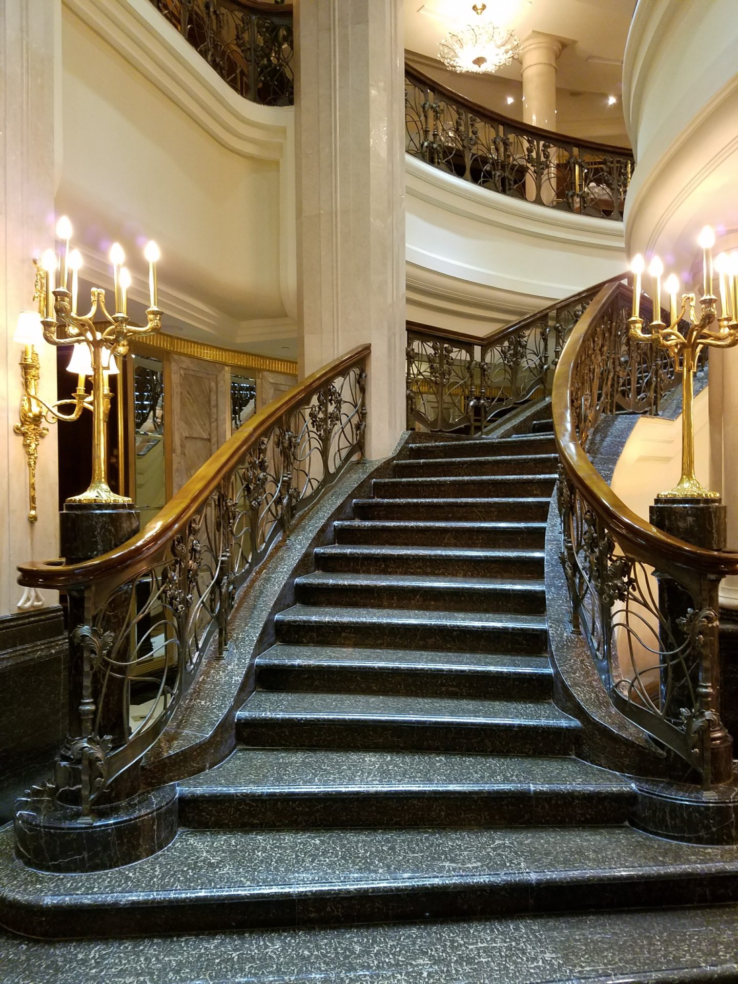 a staircase with chandeliers and a marble staircase