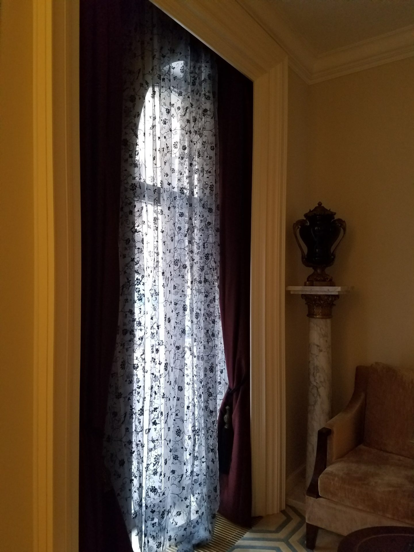 a window with curtains and a vase in the background