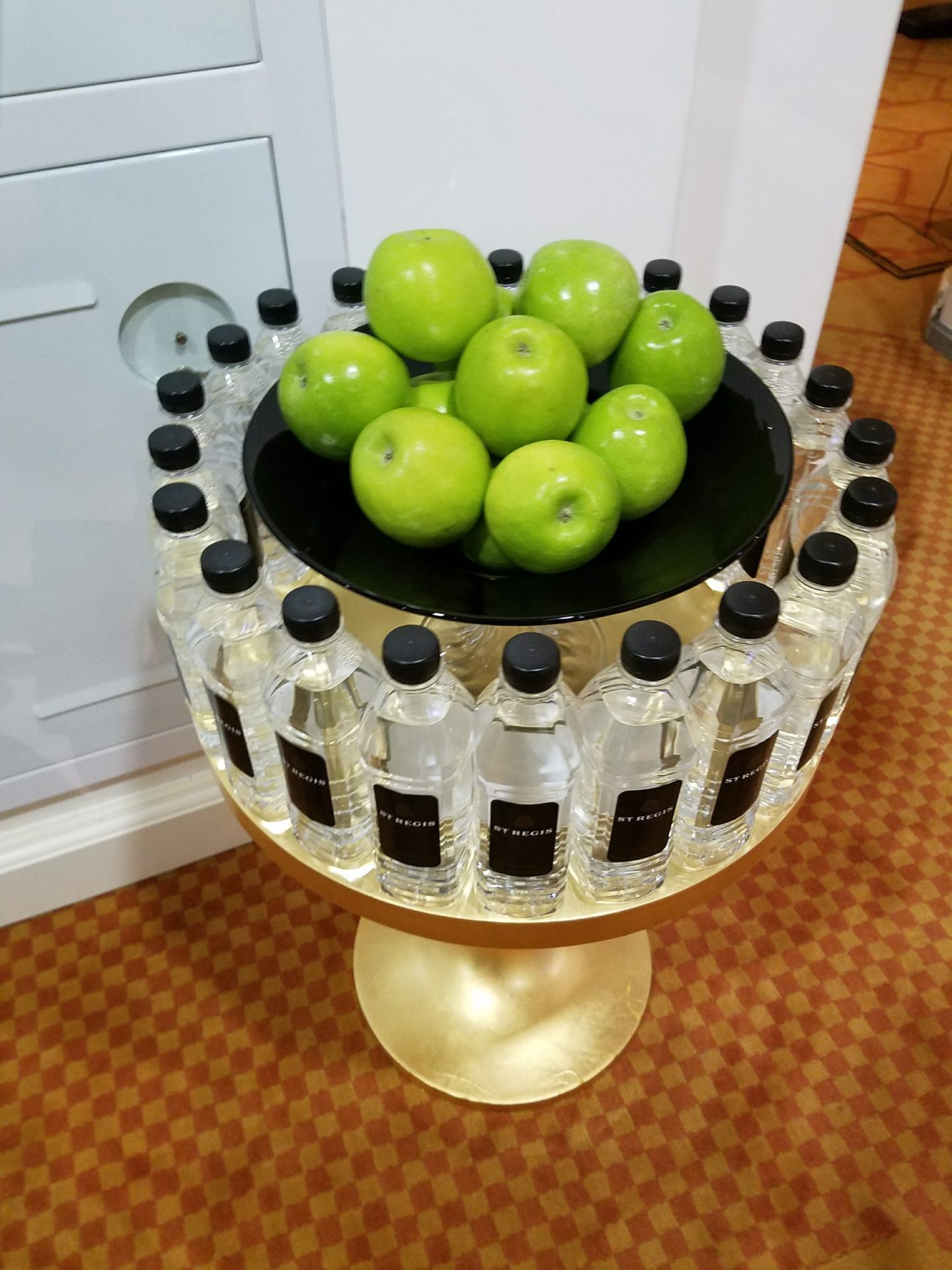 a group of bottles of water and a bowl of green apples
