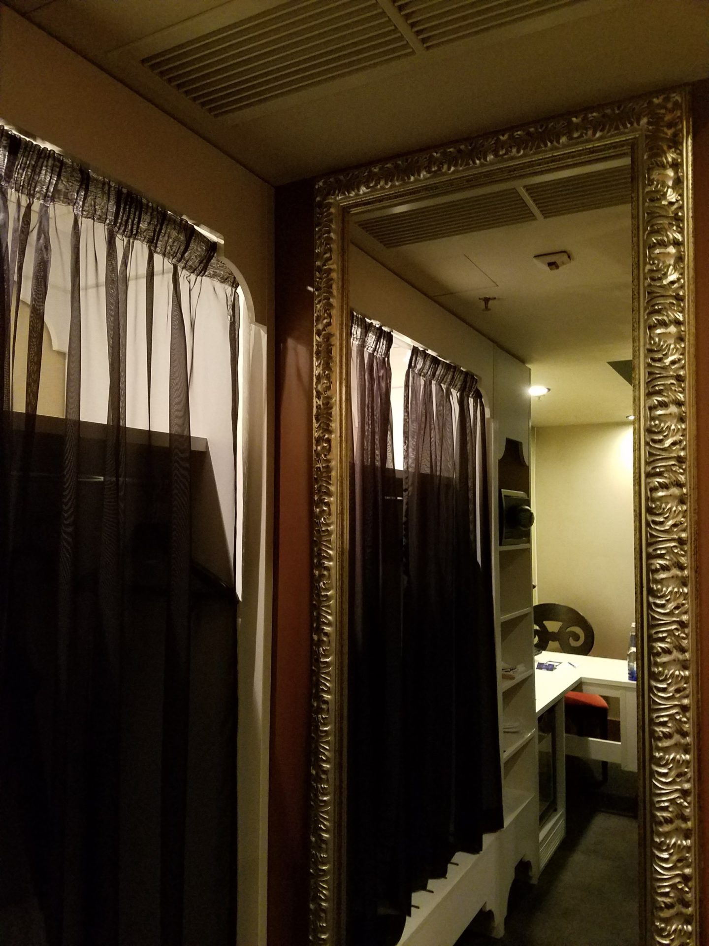 a mirror with a gold frame and curtains
