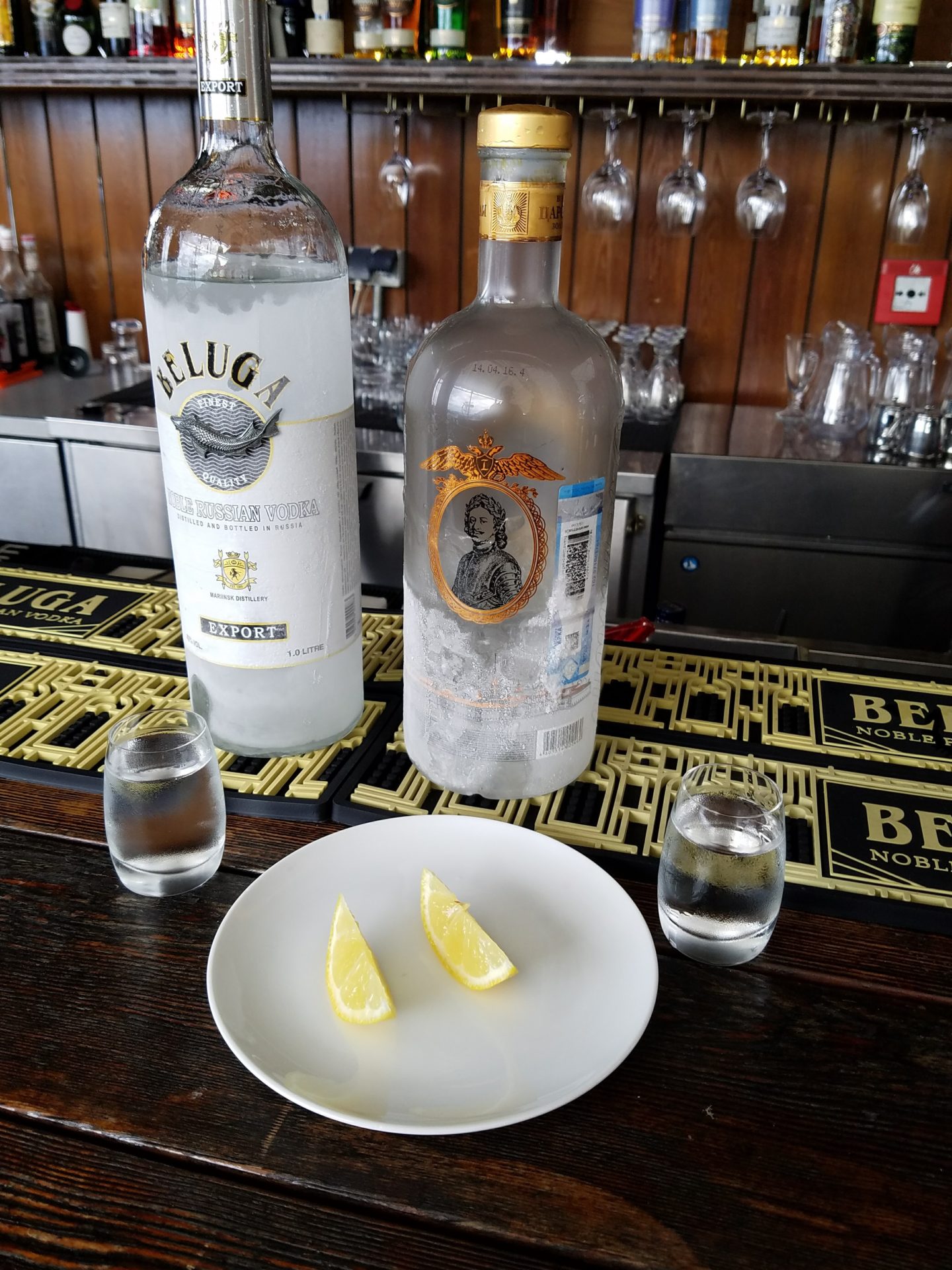 two bottles of alcohol and a plate of lemons on a bar