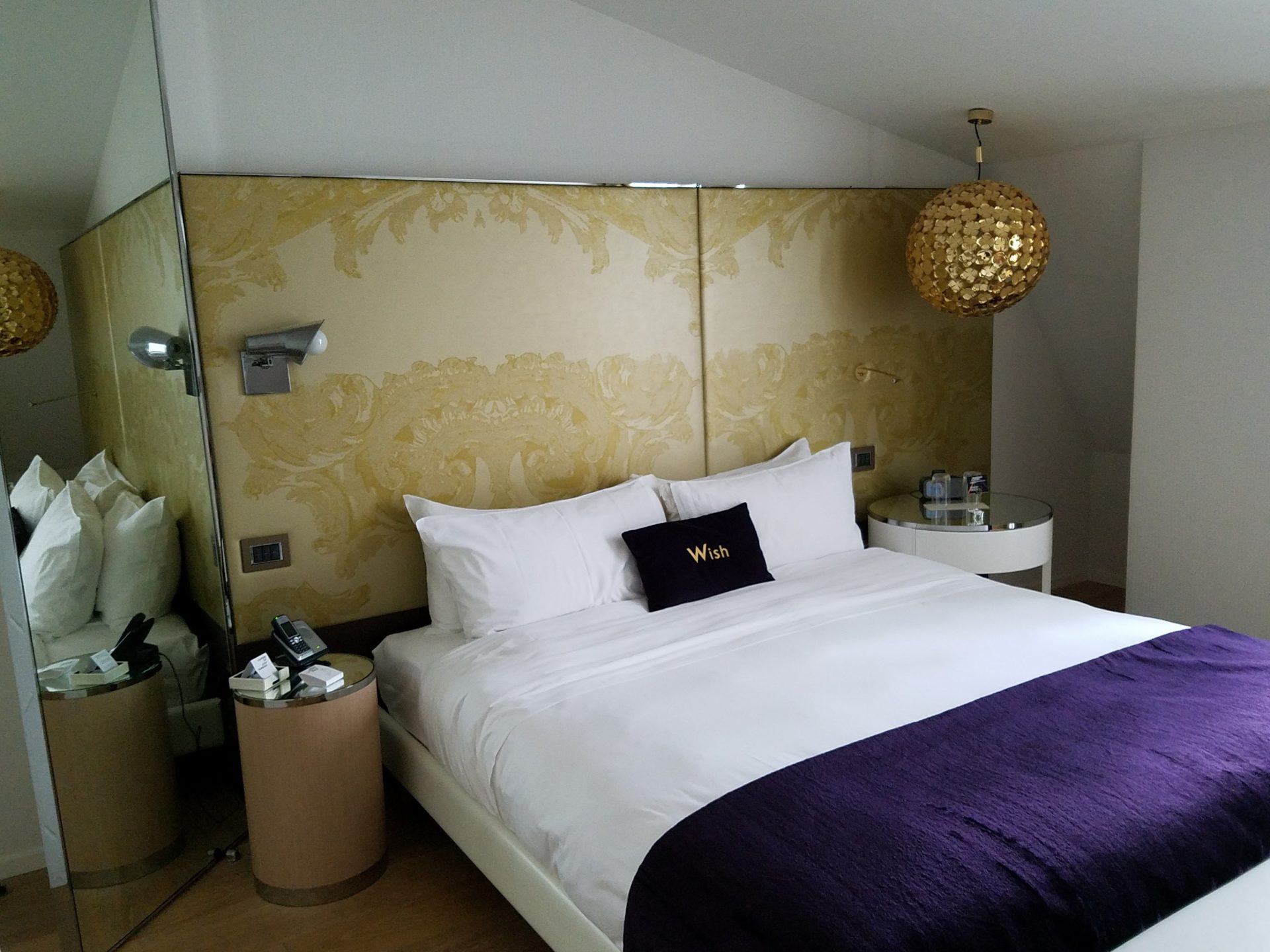 a bed with a purple blanket and a gold wall
