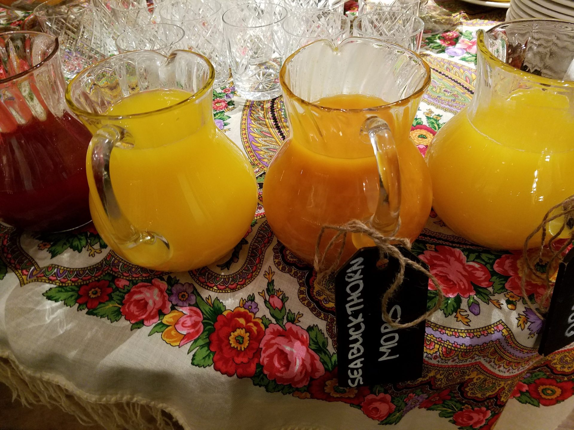 a group of glasses and pitcher of orange juice on a table