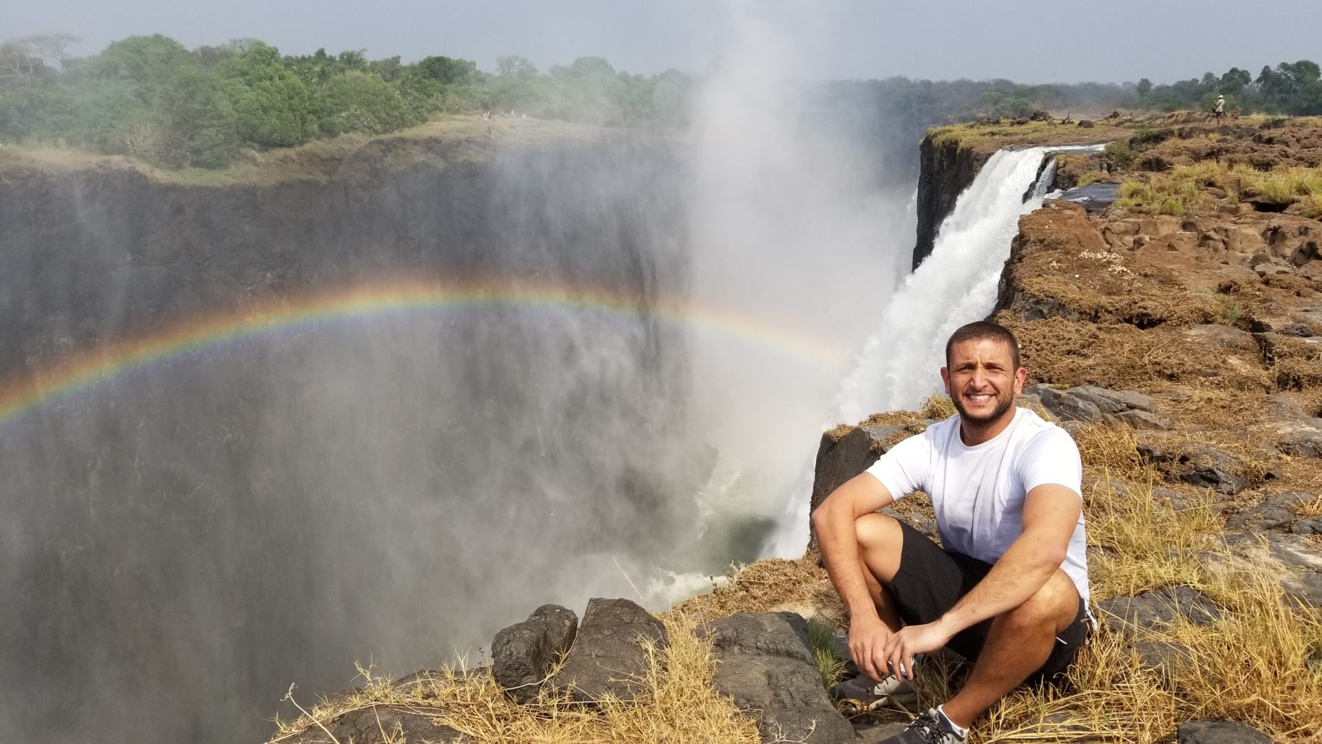 a man sitting on rocks next to Victoria Falls