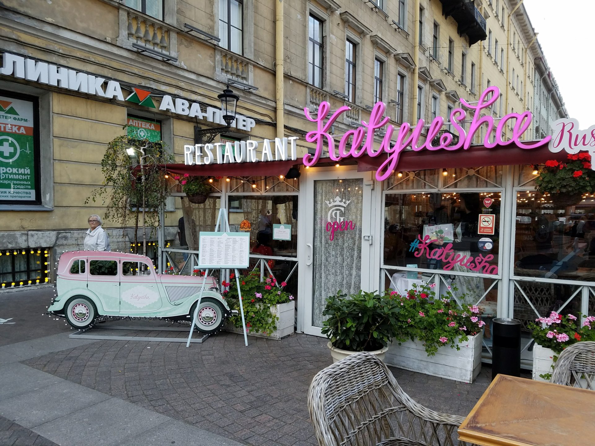 a restaurant with pink sign and a car in front of it