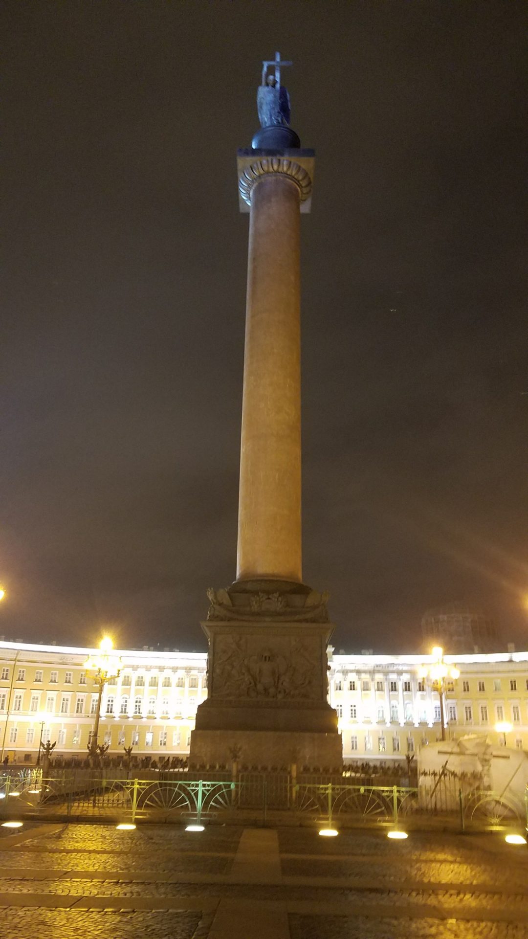 a tall pillar with a statue in front of a building