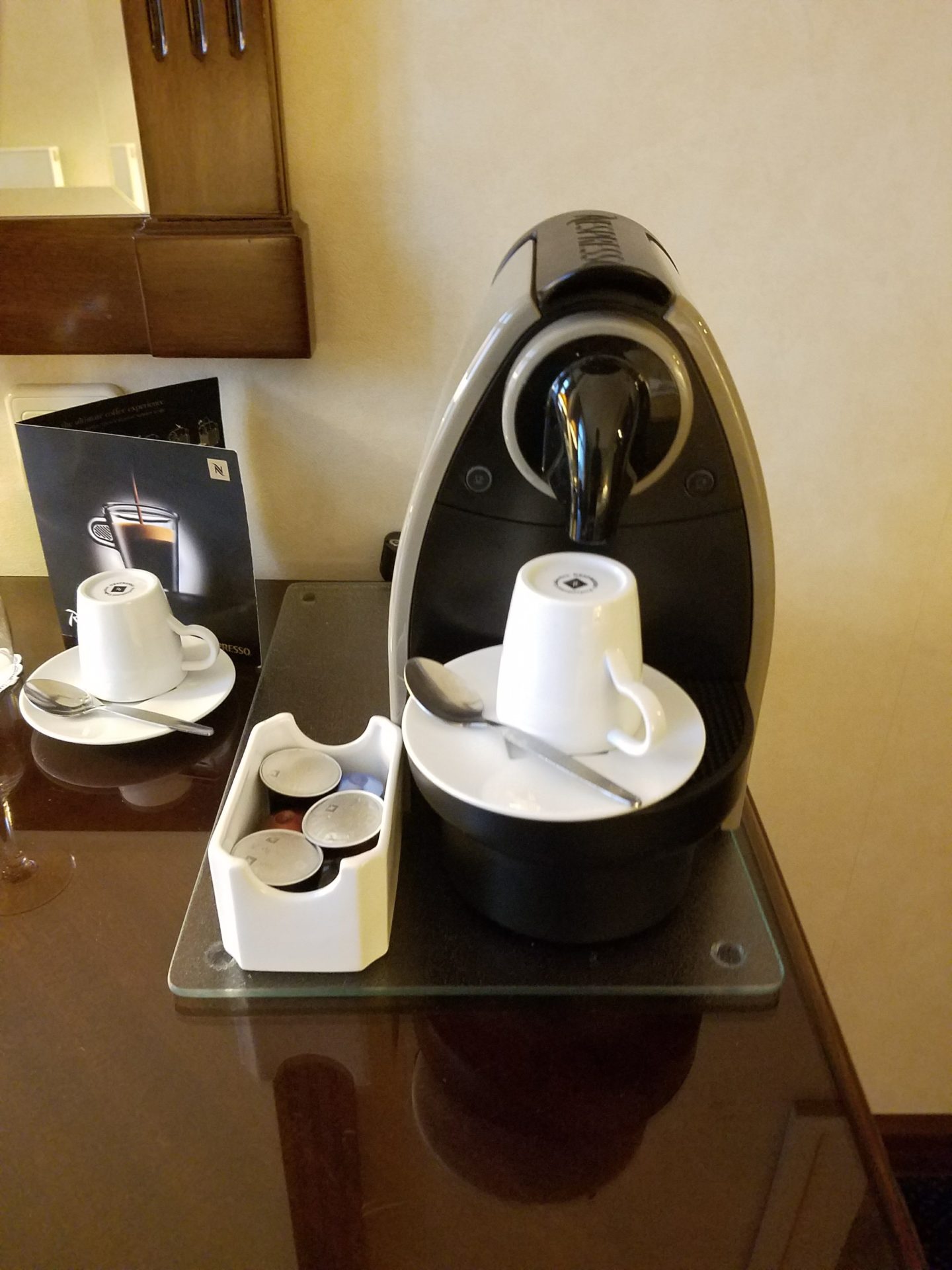 a coffee machine with a cup and spoon on a glass table