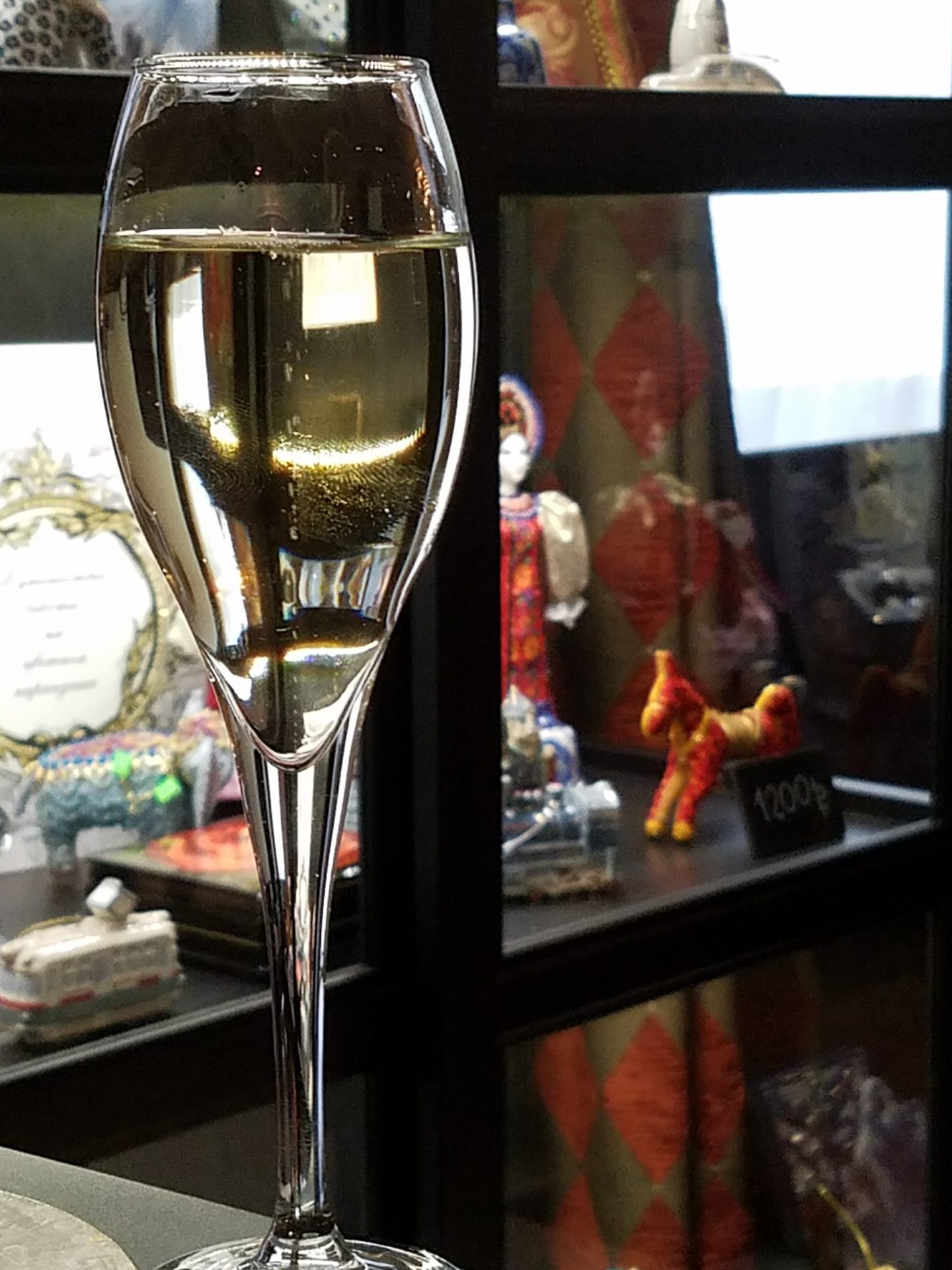a glass of champagne in front of a display case