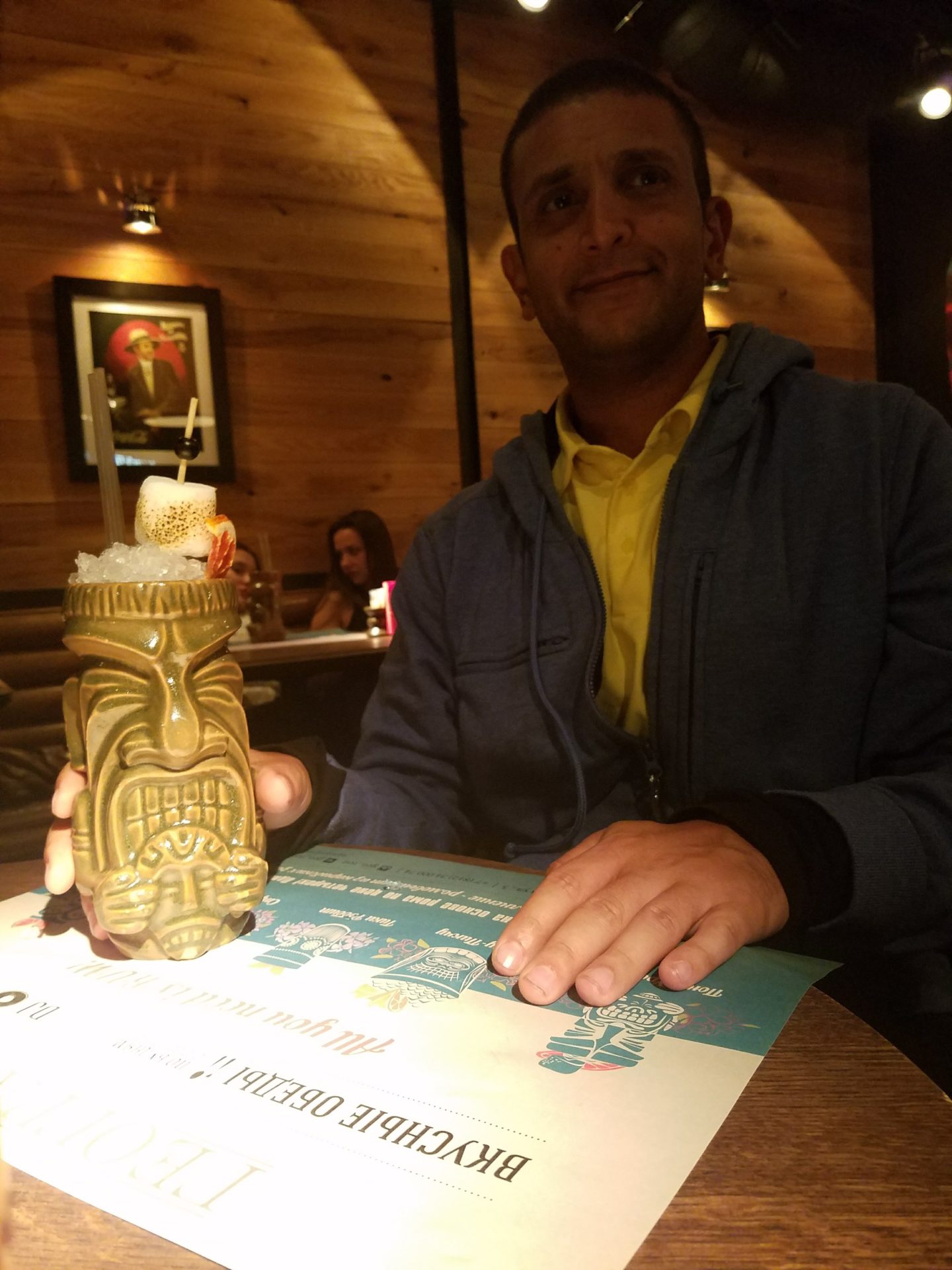 a man sitting at a table with a tiki statue