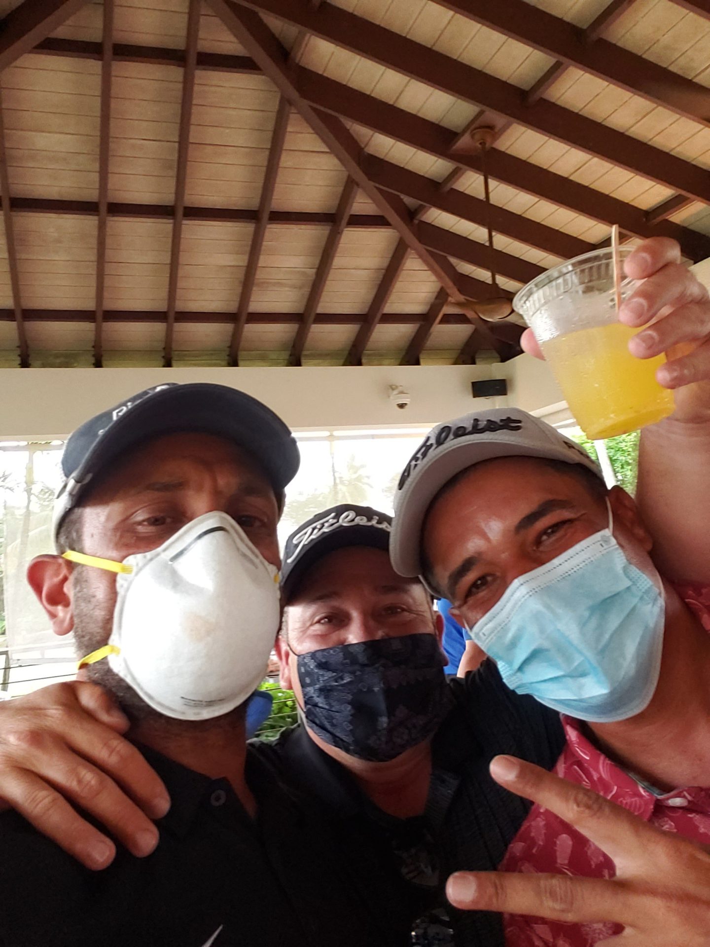 a group of men wearing face masks and holding a drink