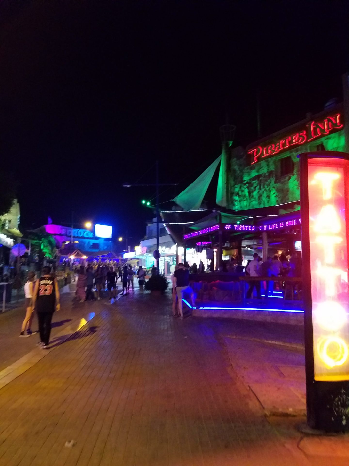 a street with people walking and neon signs