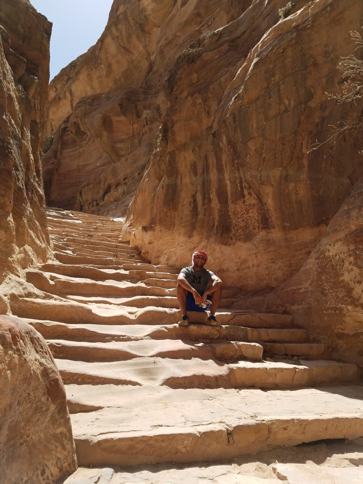 a man sitting on a stone staircase in a canyon