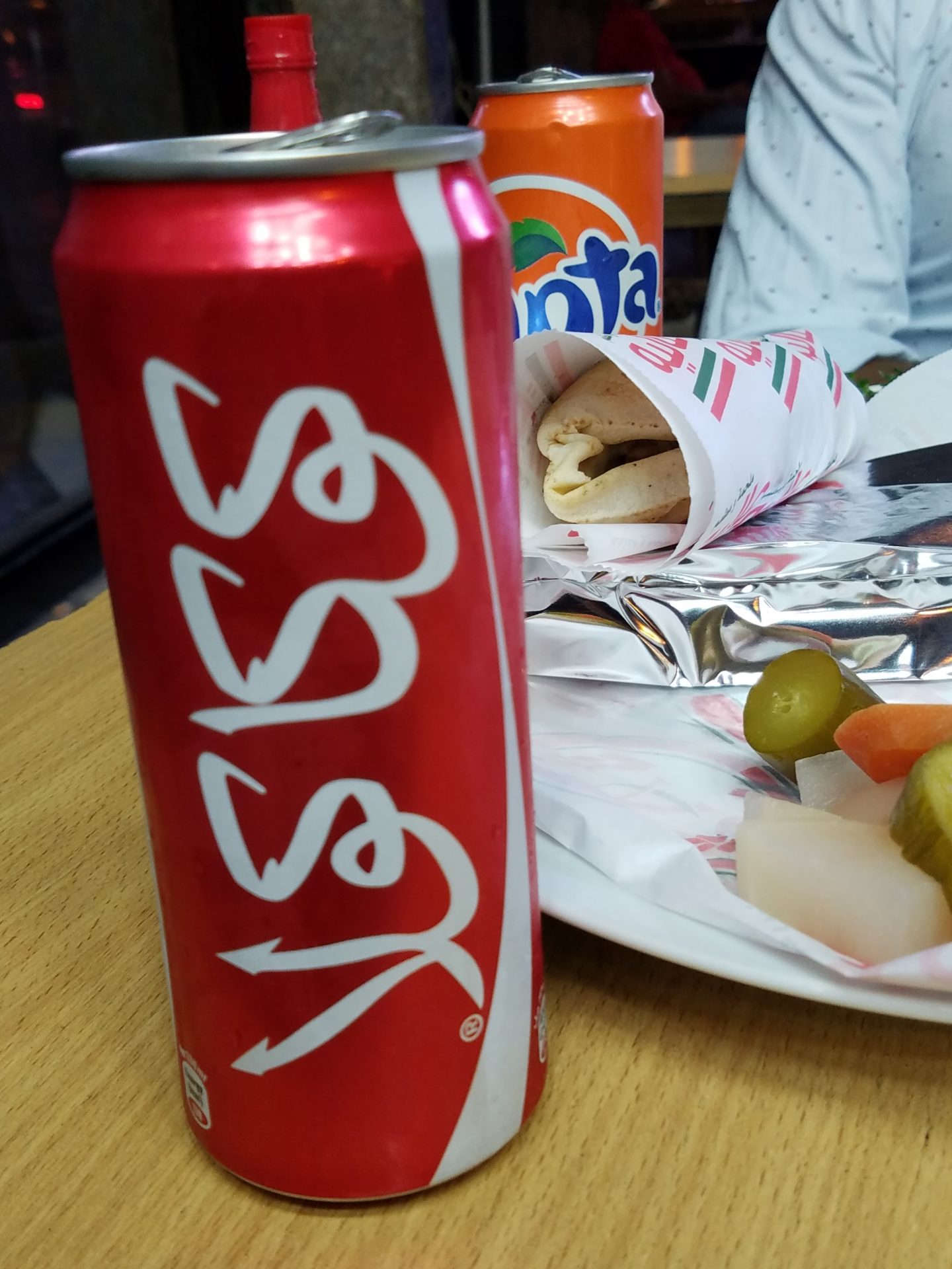 a red can of soda next to a plate of food