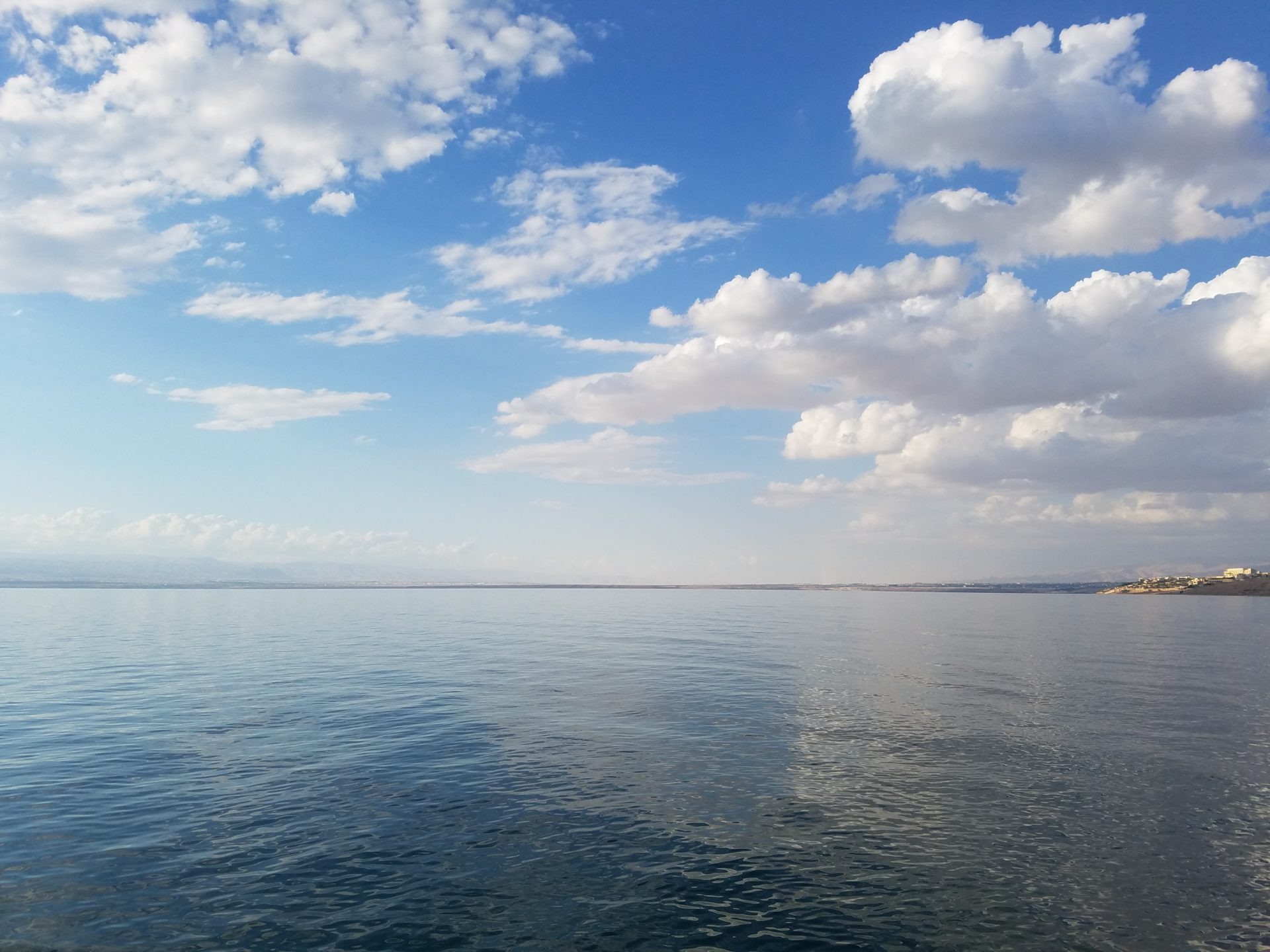a body of water with clouds and blue sky