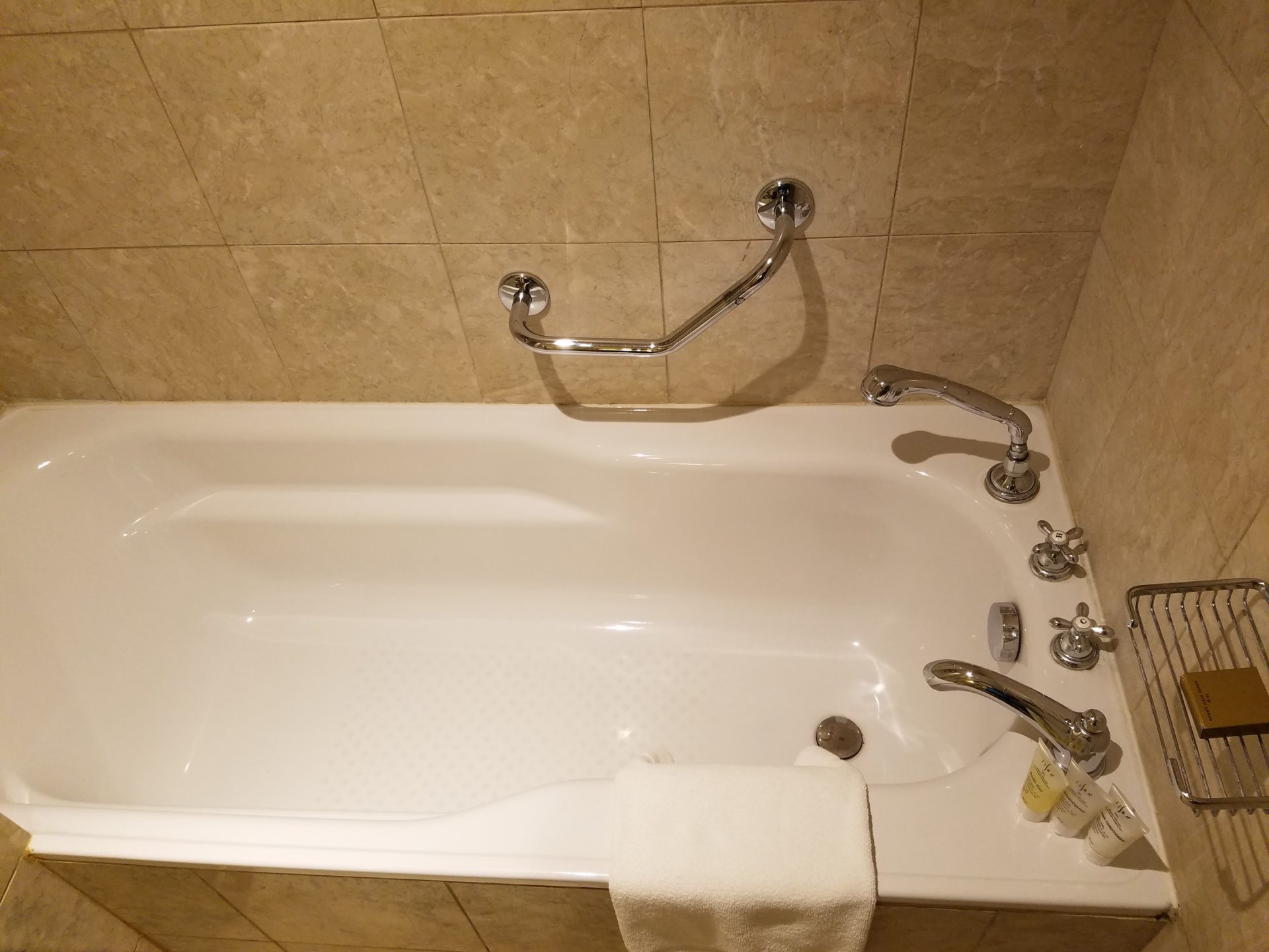 a bathtub with faucets and a towel from the wall