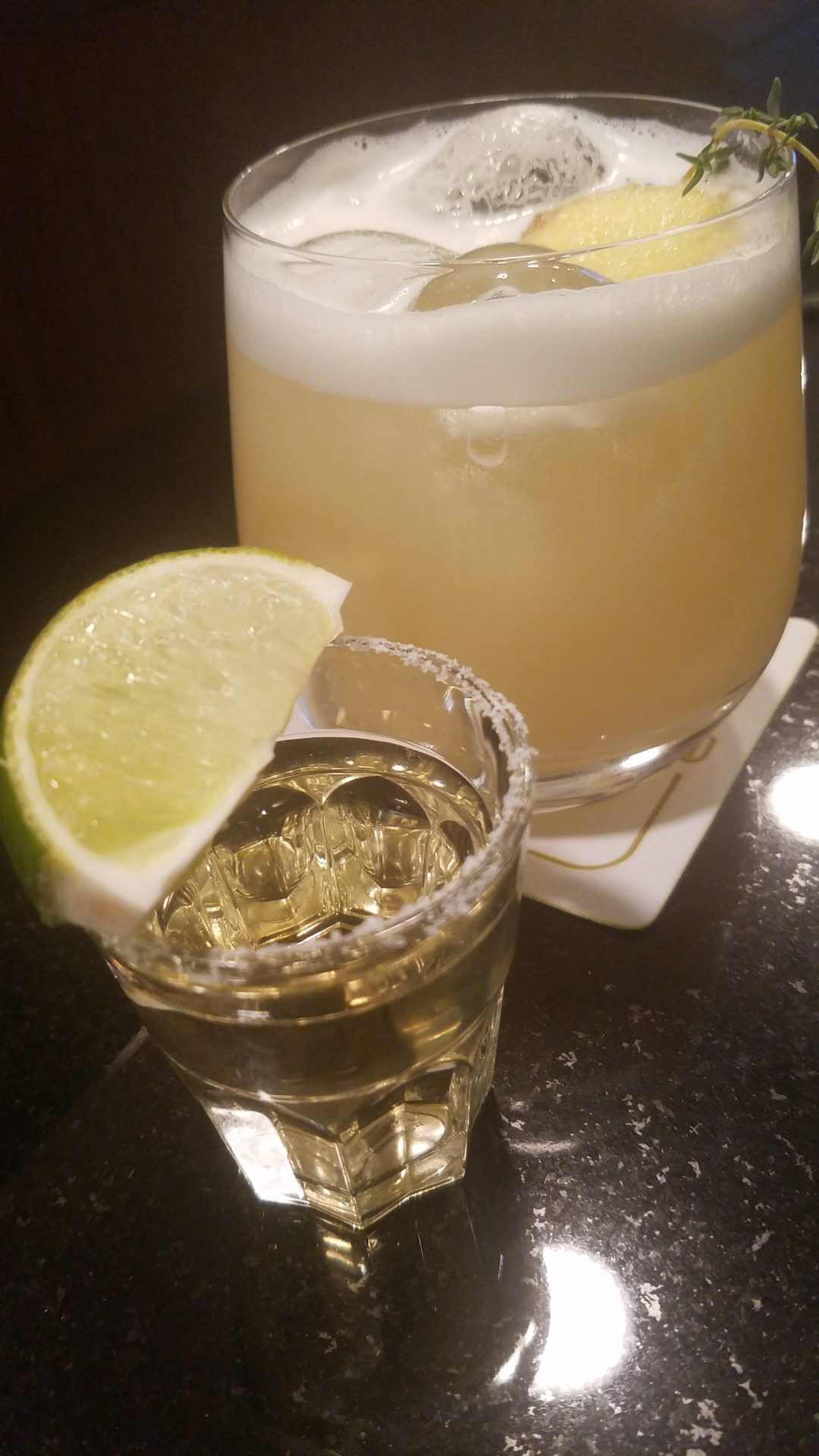 a glass of alcohol with a lime wedge on top