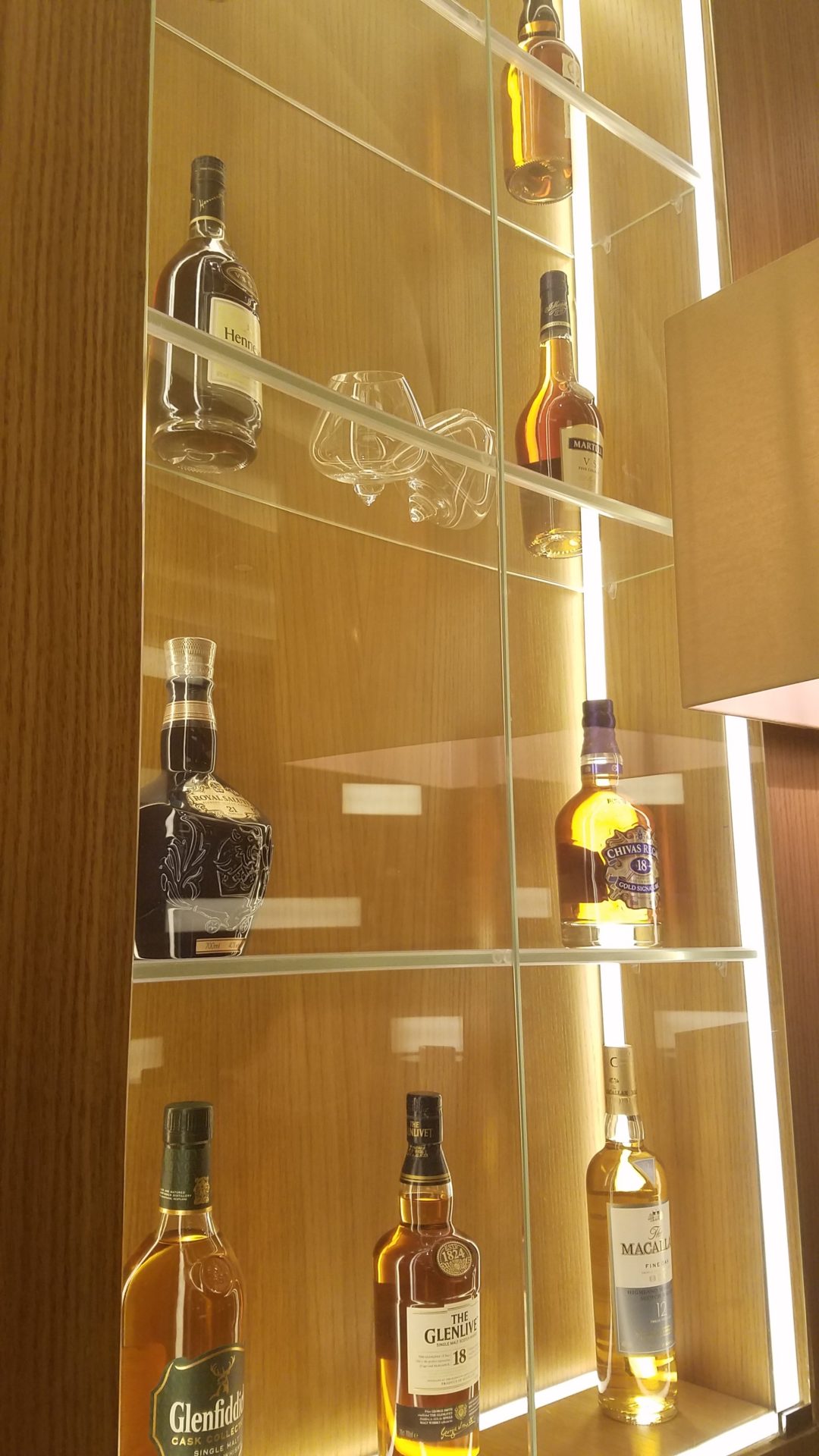 a glass shelf with bottles of alcohol