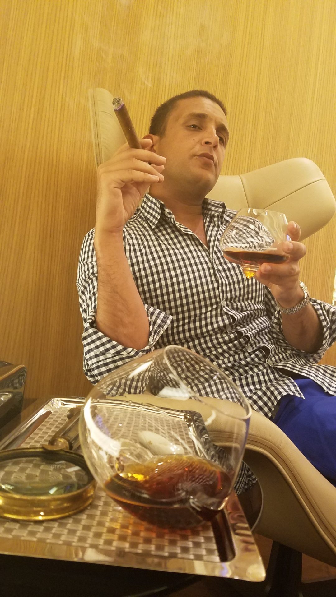 a man sitting in a chair holding a cigar and a glass of alcohol