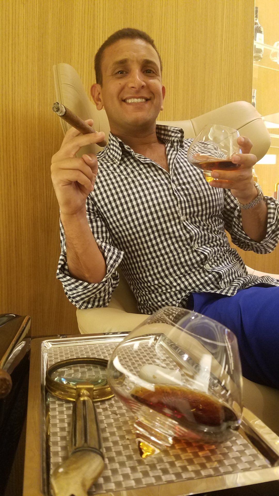 a man sitting in a chair holding a cigar and a glass of alcohol