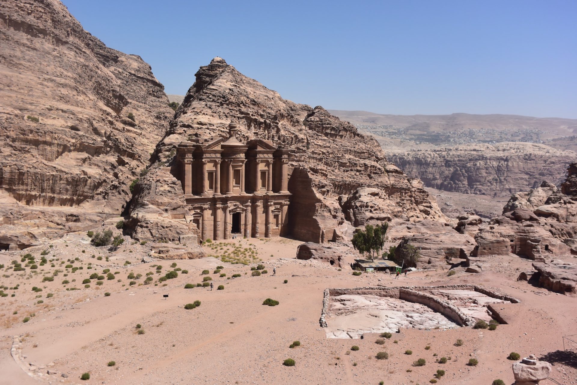 a stone building in a desert with Petra in the background