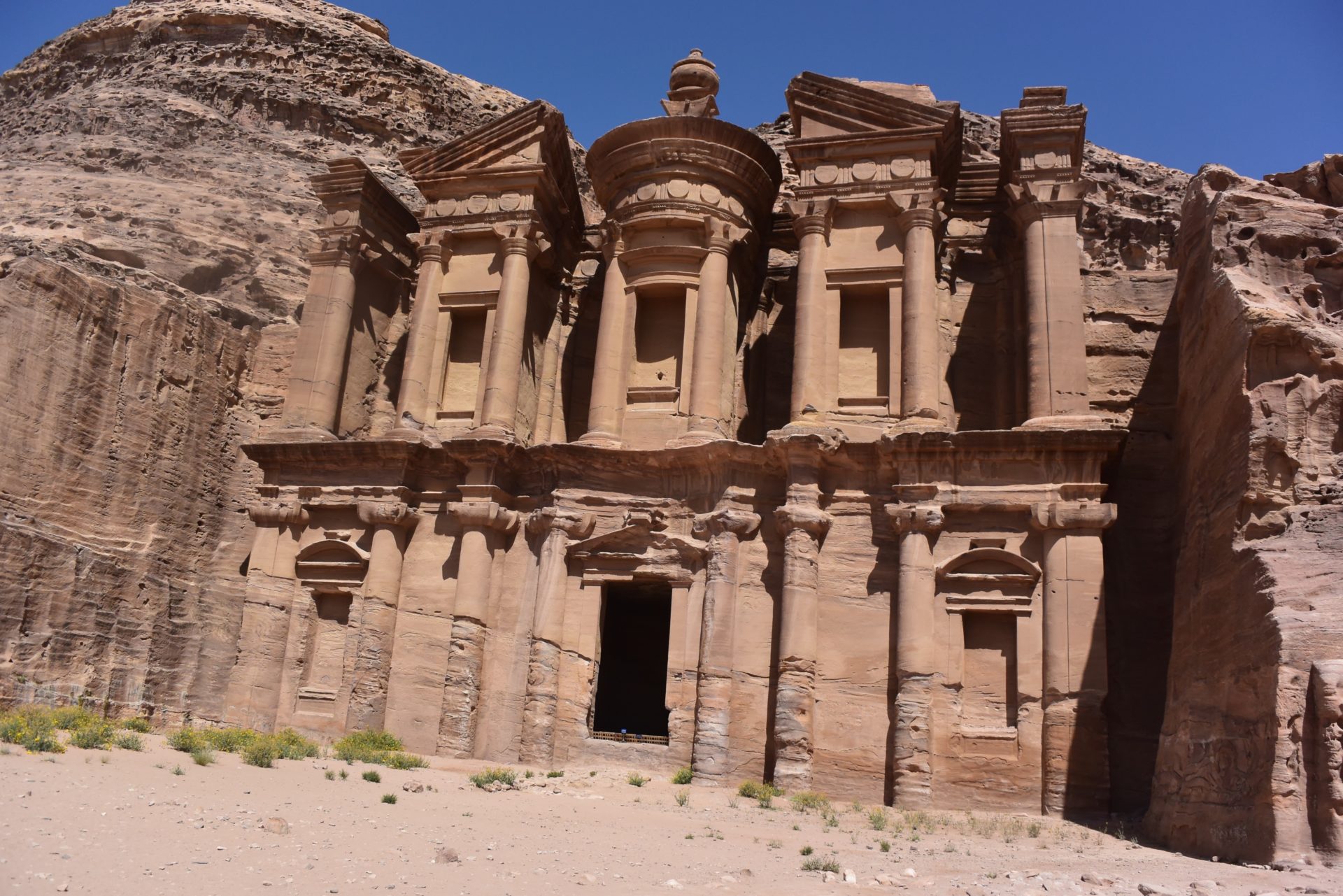 a stone building with columns with Petra in the background