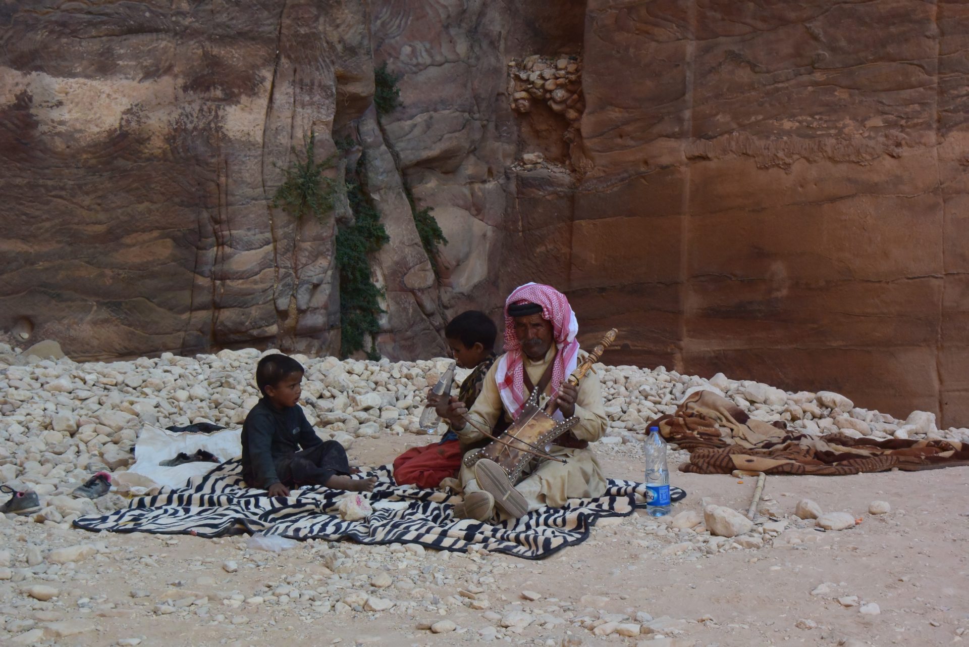 a man and boy sitting on a blanket playing music
