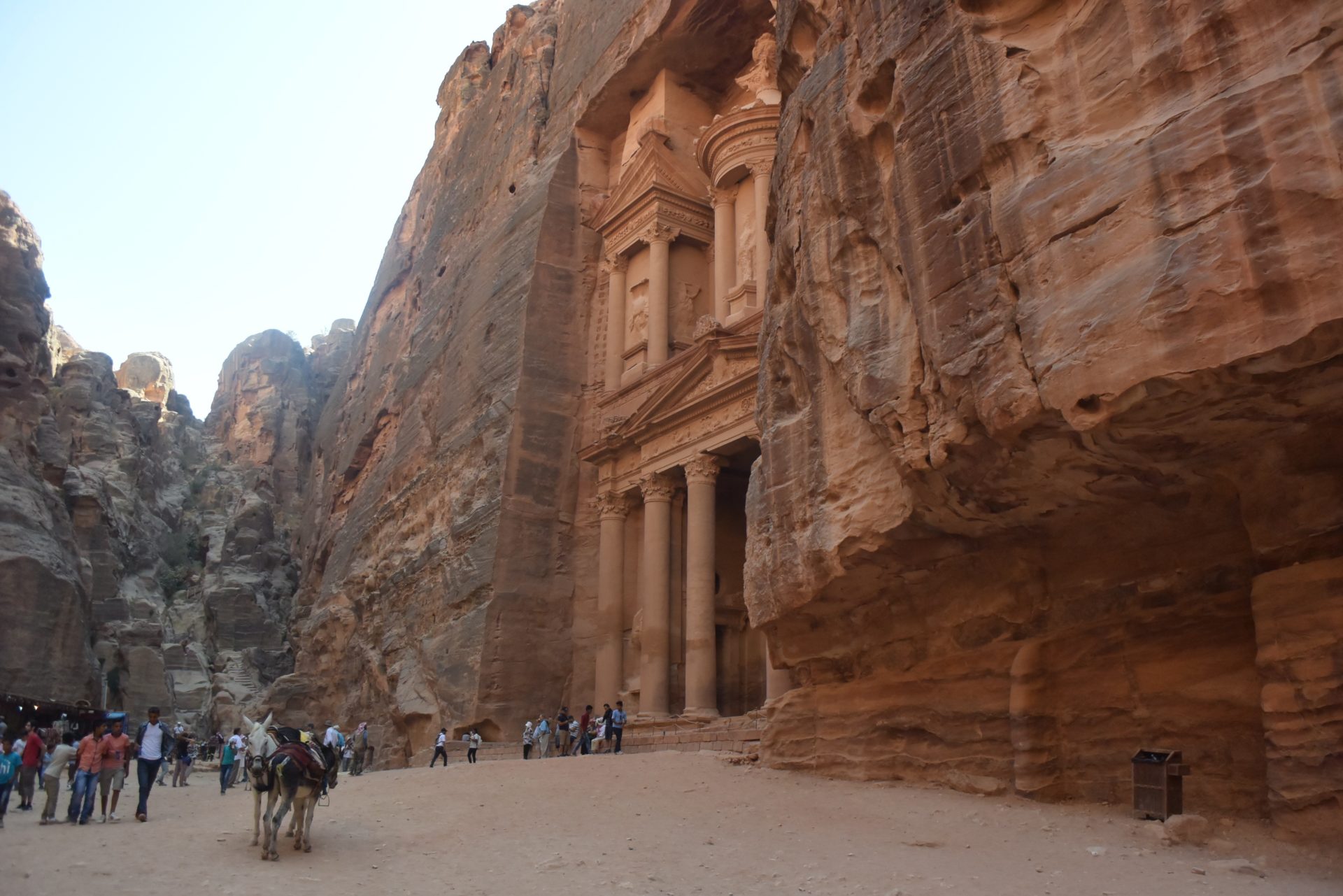 people walking in front of a rock cliff with Petra in the background