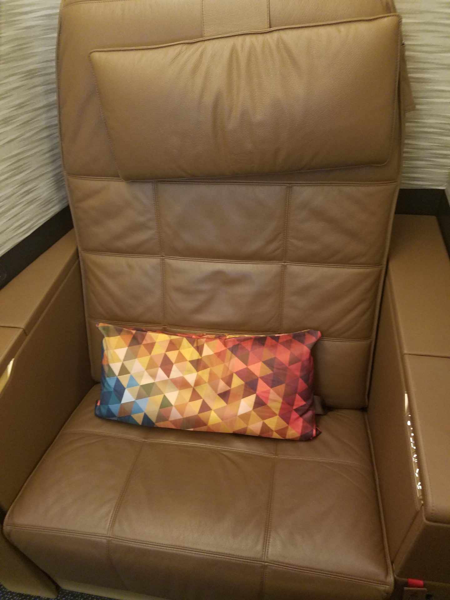 a brown recliner with a colorful pillow