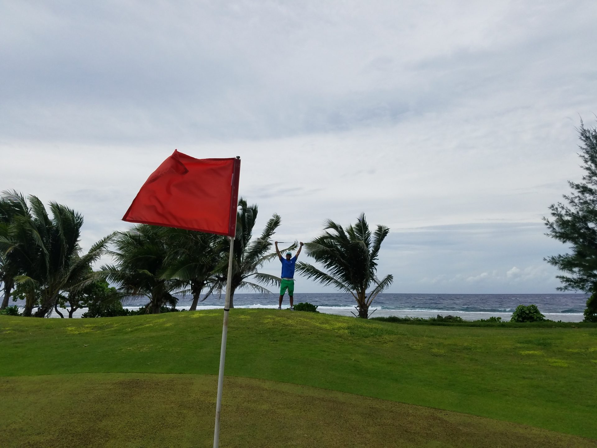 a man standing on a golf course with a flag in the air