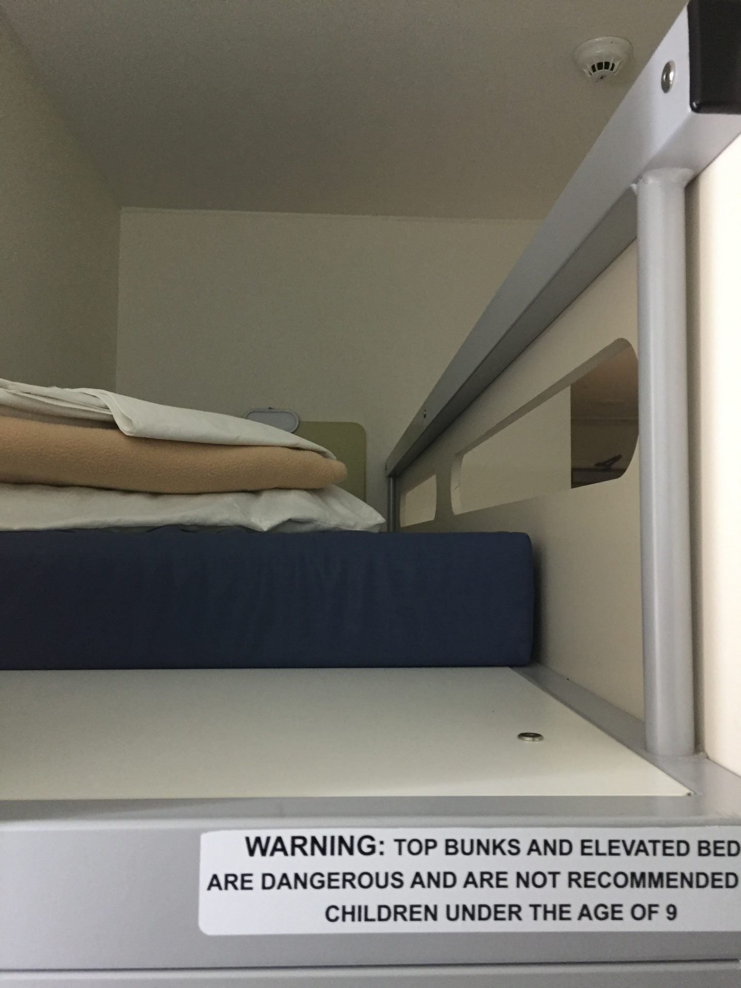 a bunk bed with a stack of blankets