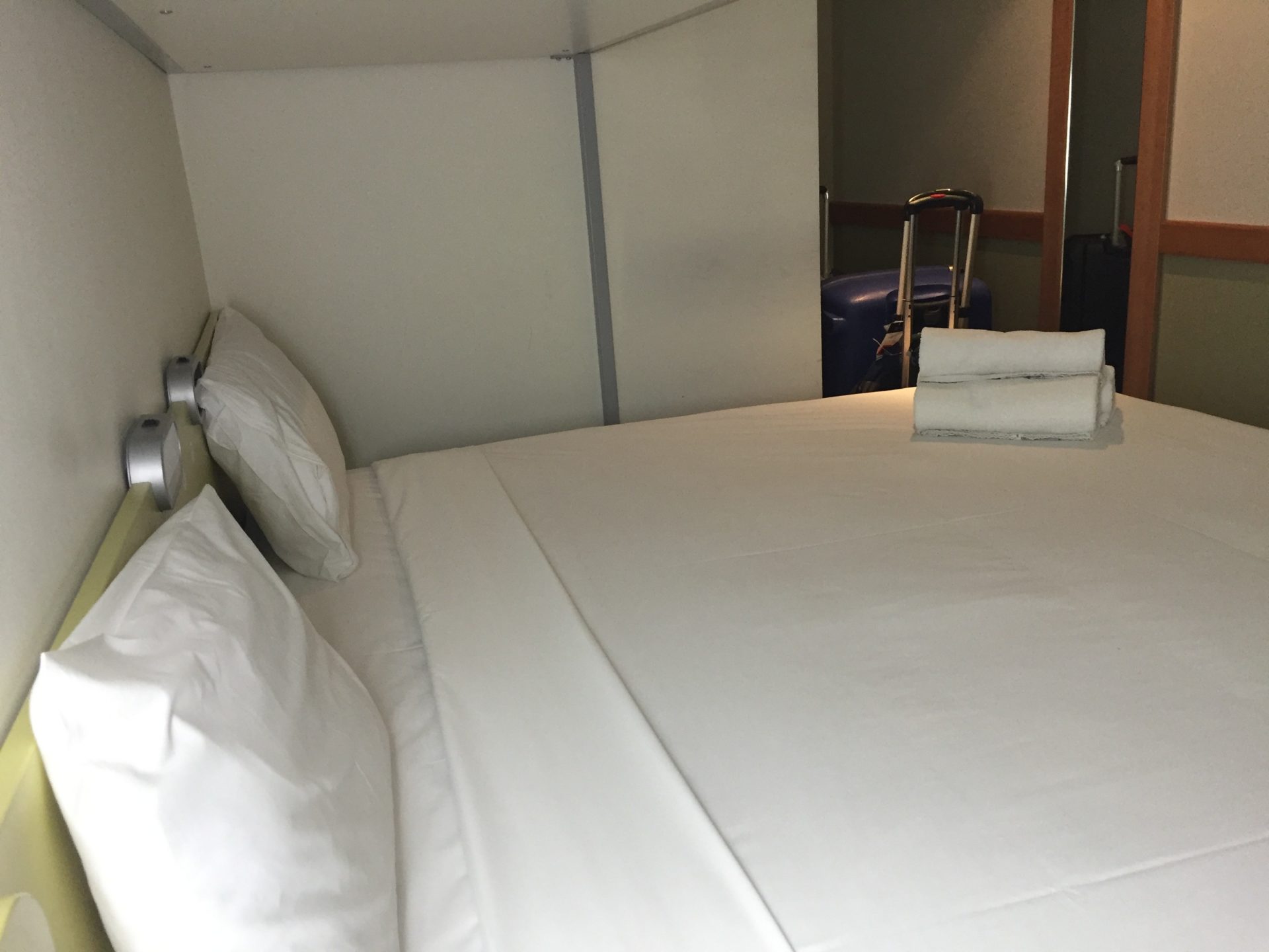 a bed with white sheets and a suitcase