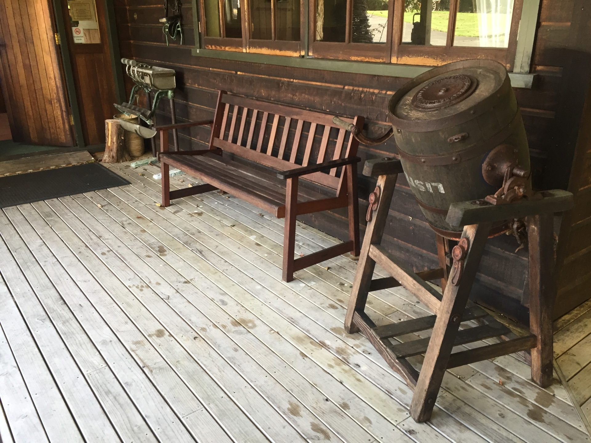 a wooden bench and a barrel on a porch