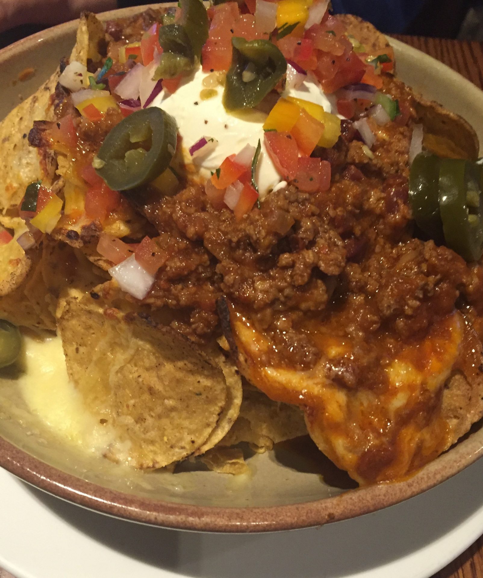 a bowl of nachos with chili and jalapenos