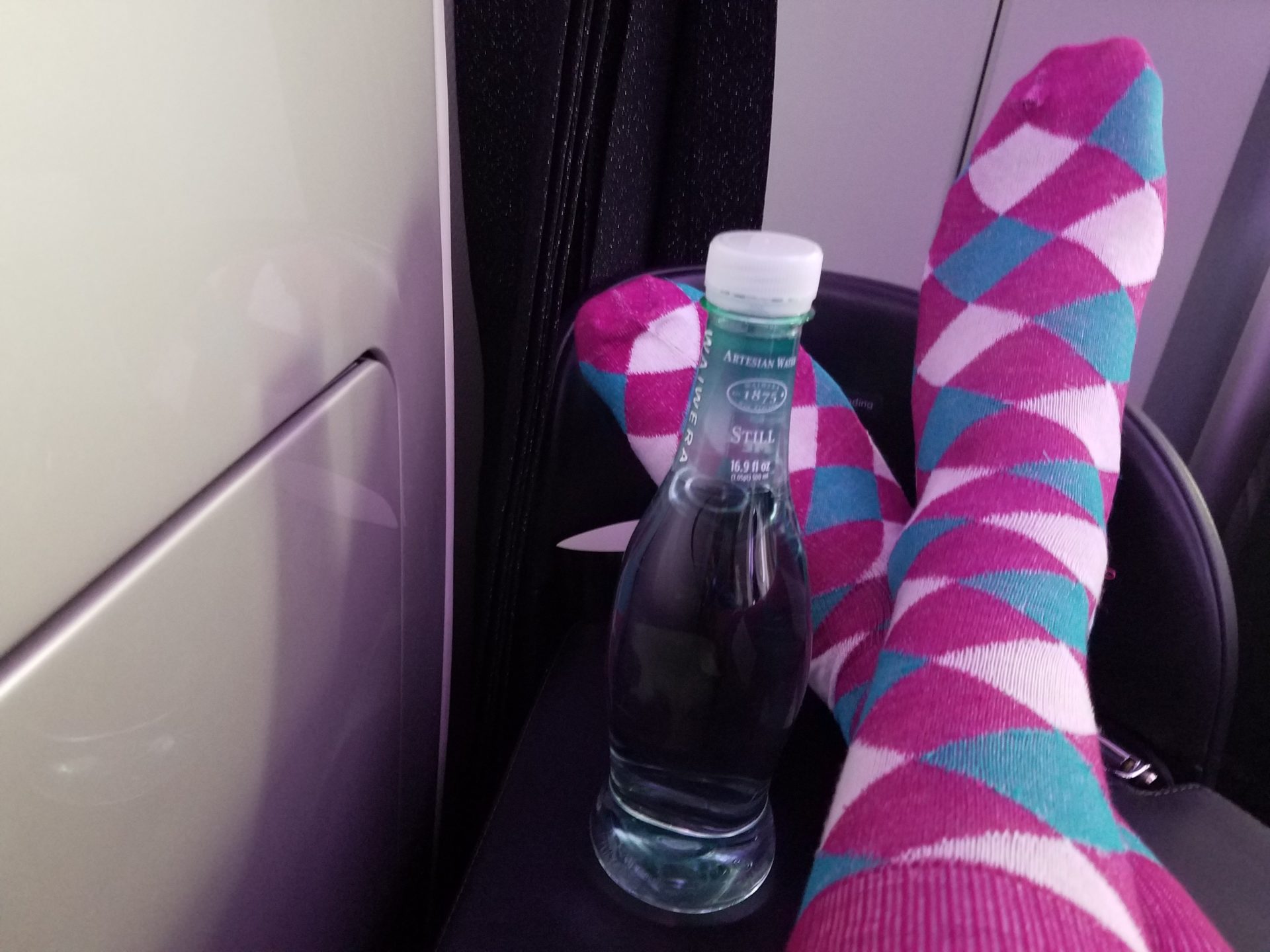 a person's feet with colorful socks and a bottle of water
