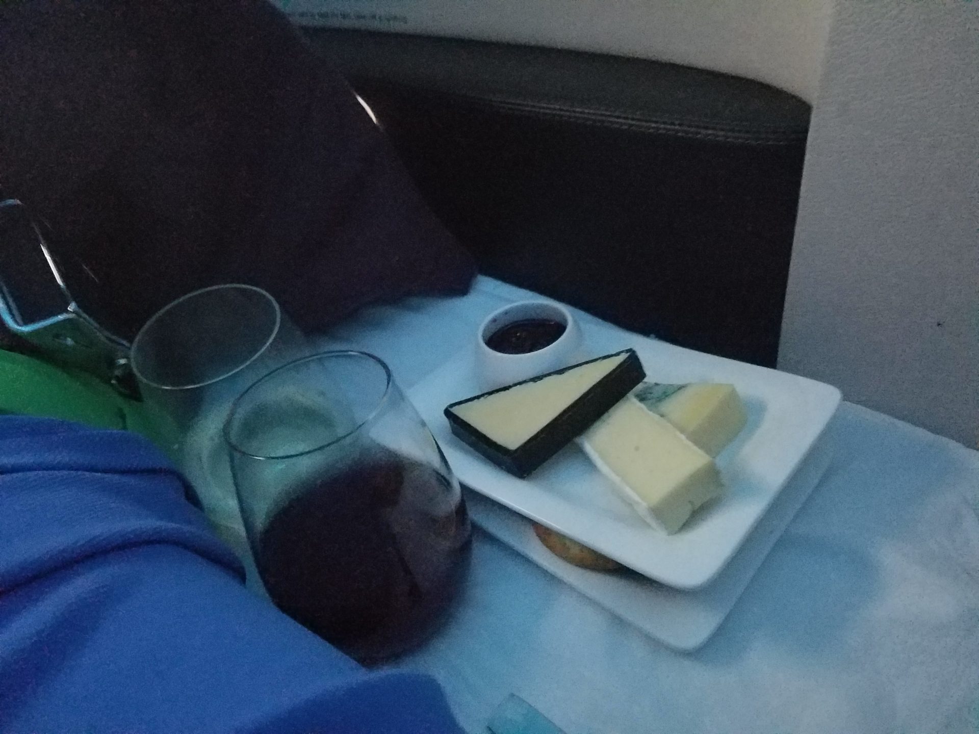 a plate of cheese and wine on a bed