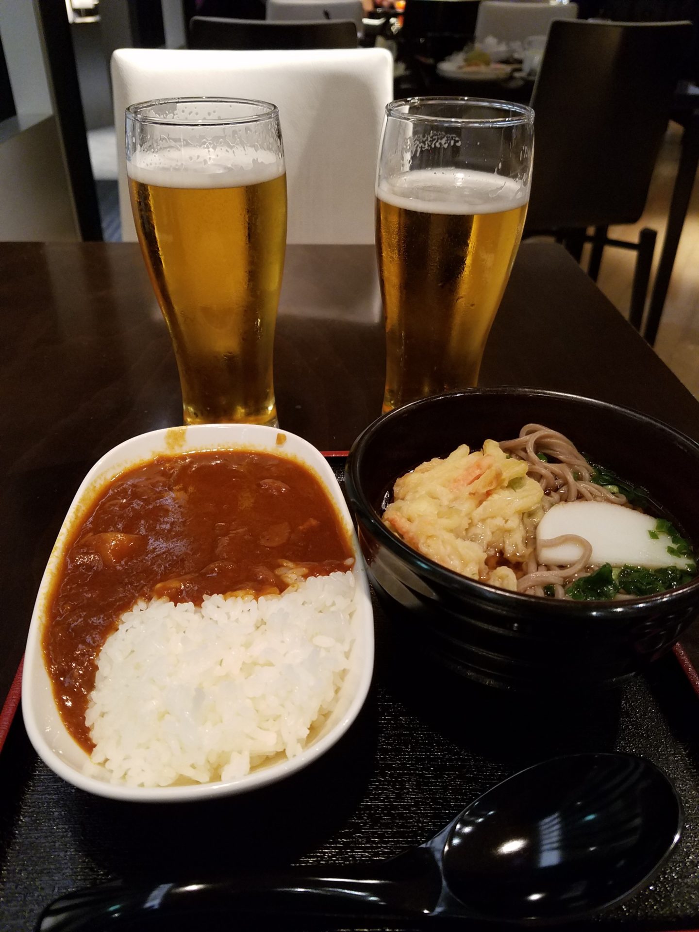 a bowl of rice and noodles with a couple glasses of beer