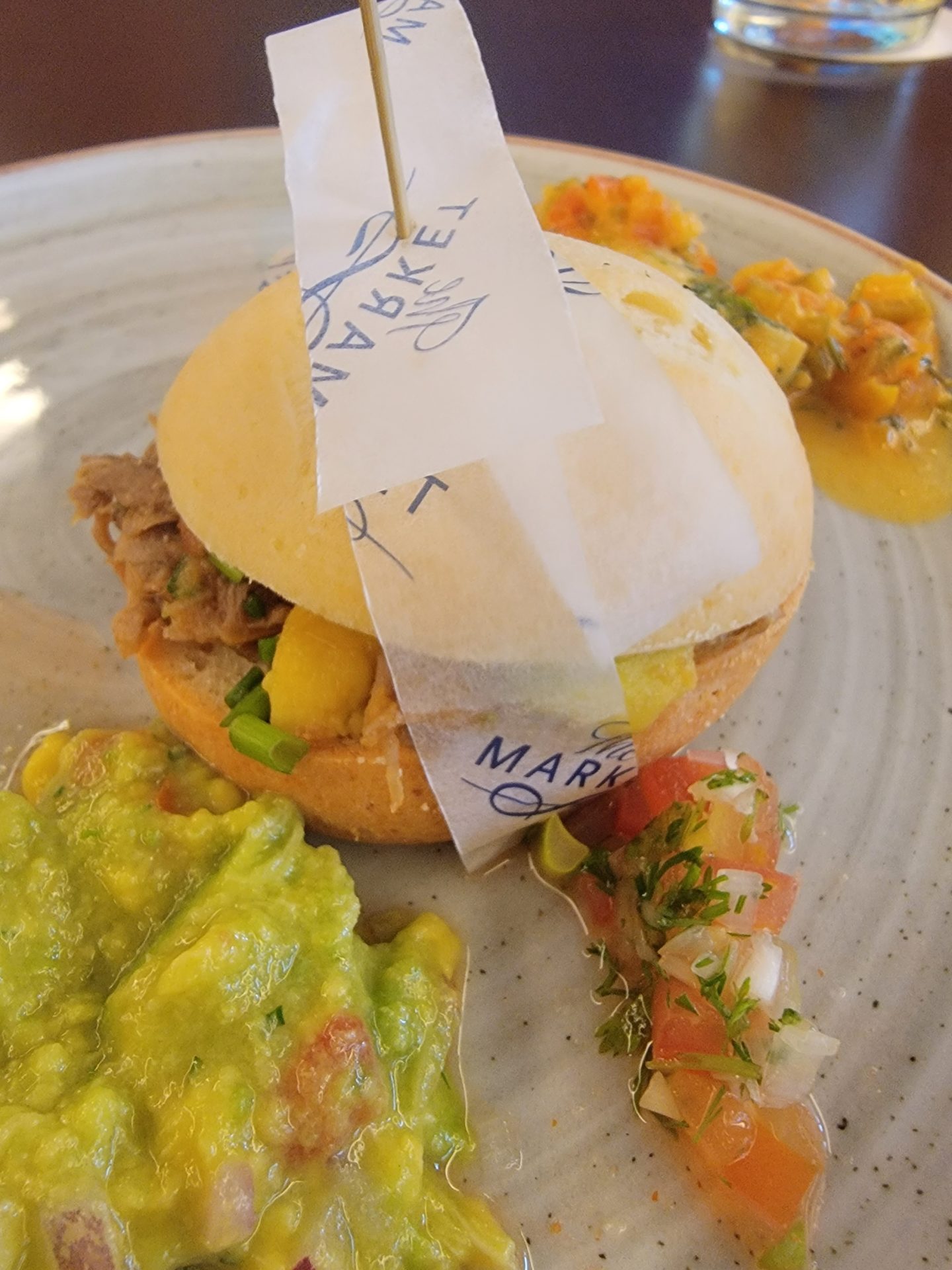 a plate of food with a small sandwich and guacamole