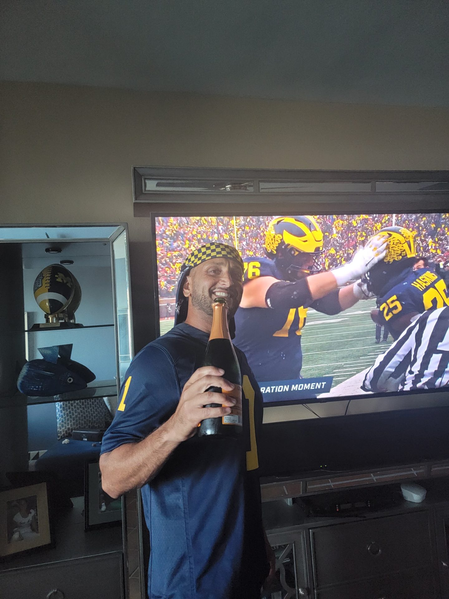 a man holding a bottle of champagne in front of a television