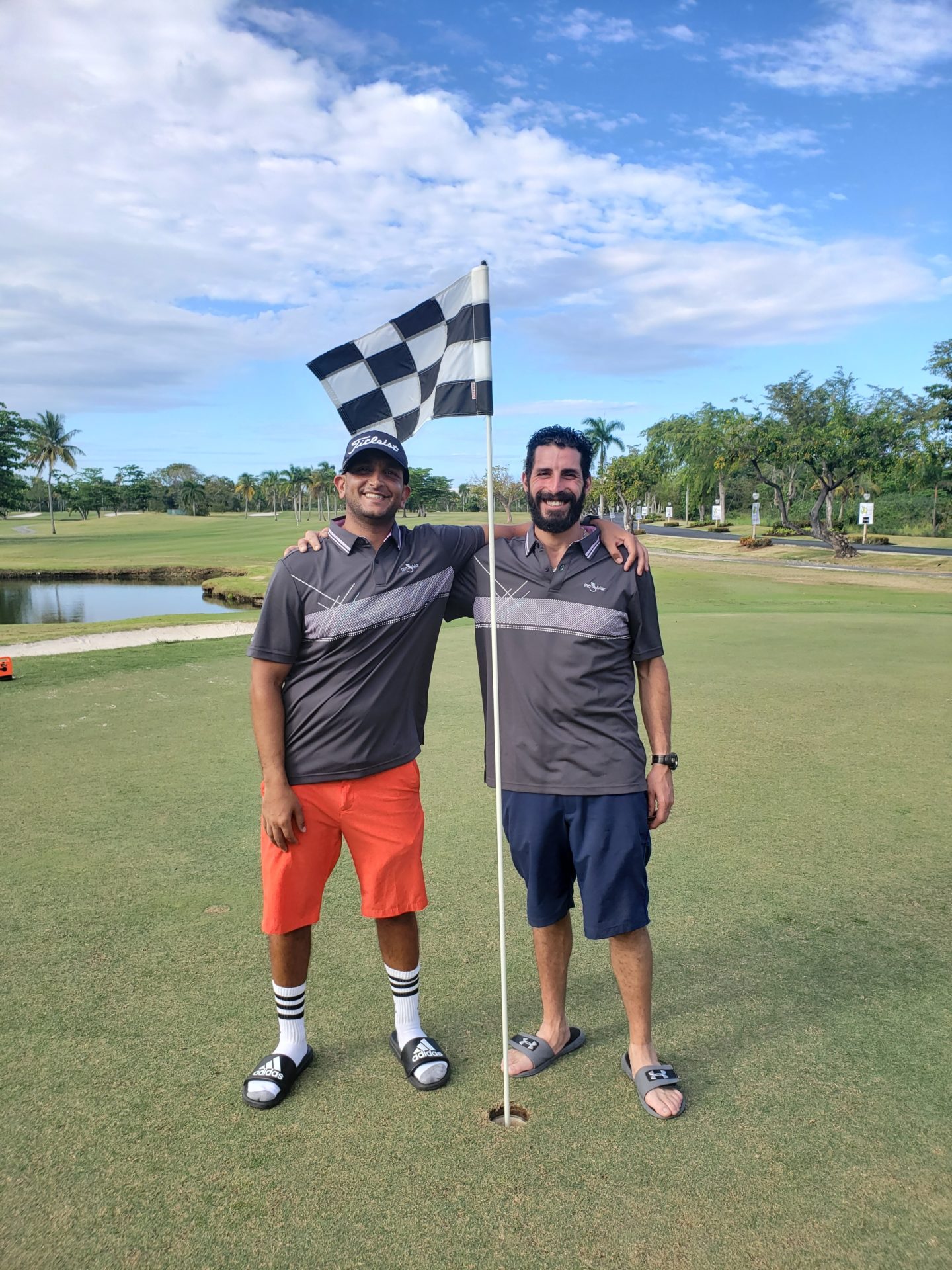 two men standing on a golf course holding a flag