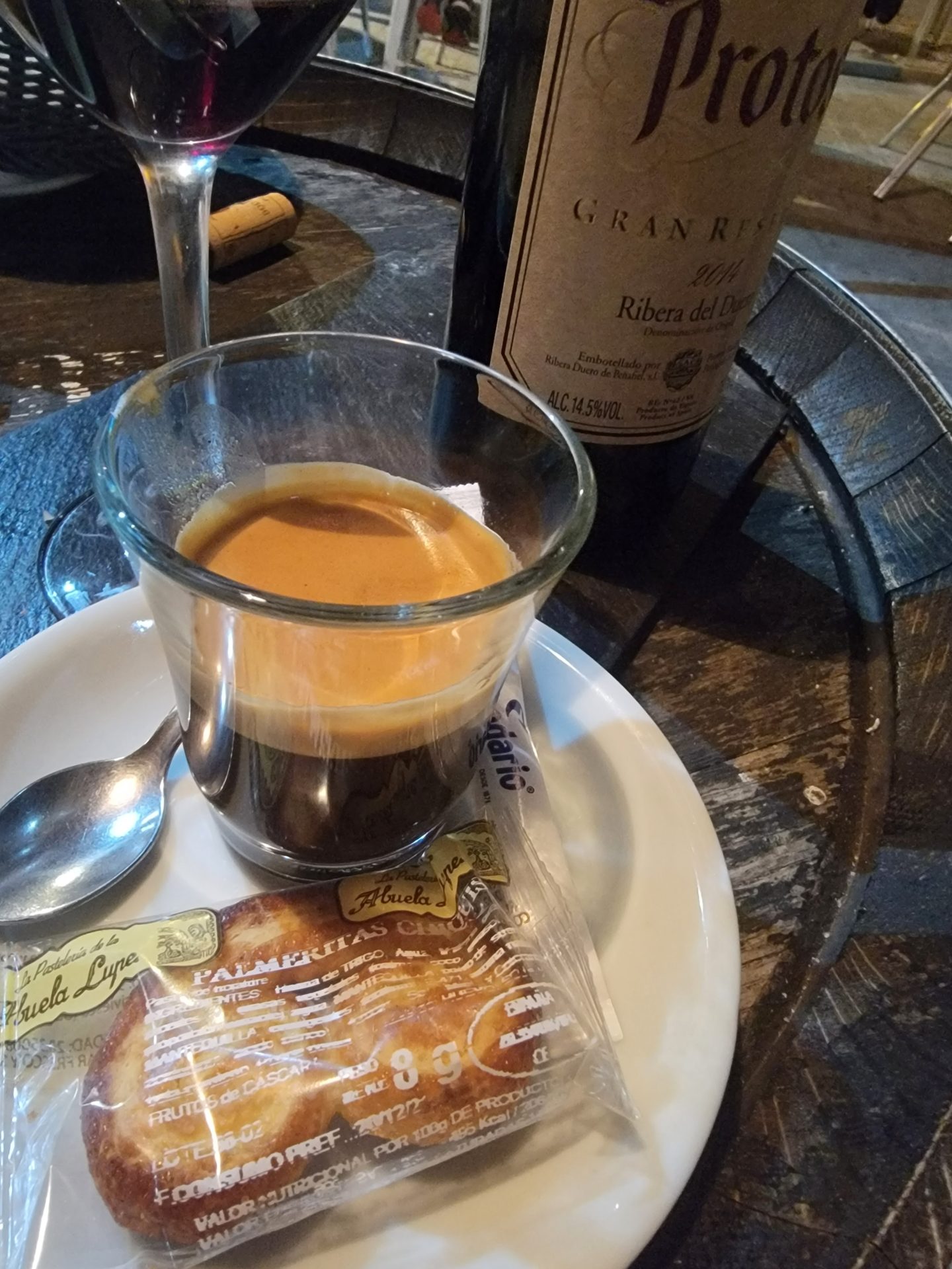 a glass of coffee on a plate with a bottle of wine
