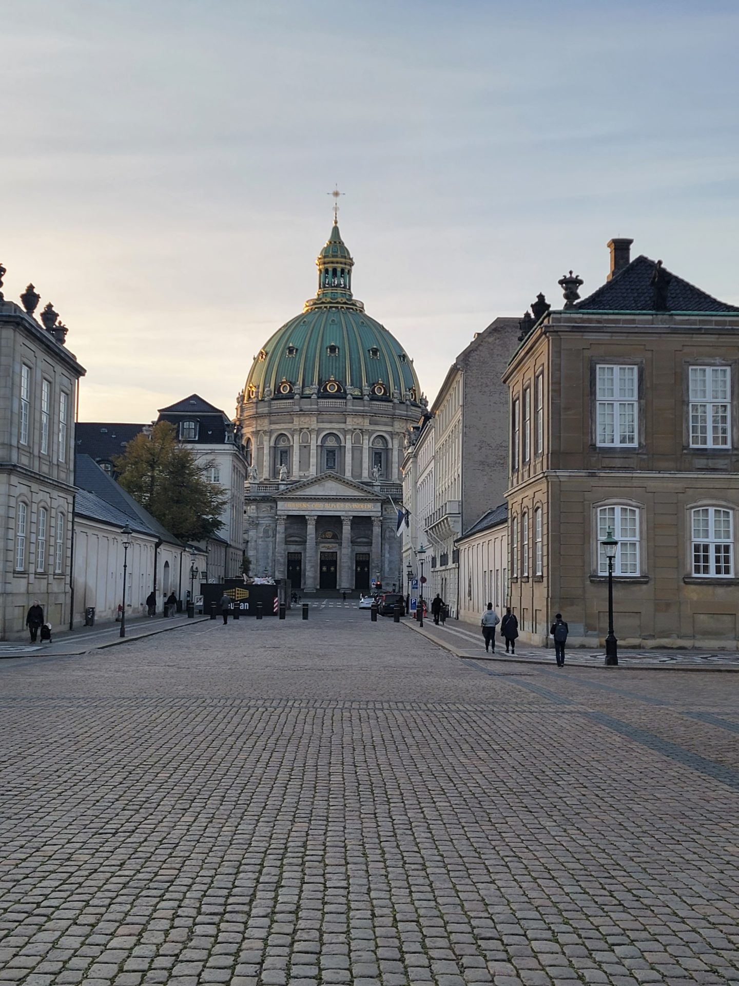 a stone street with Amalienborg and people walking around
