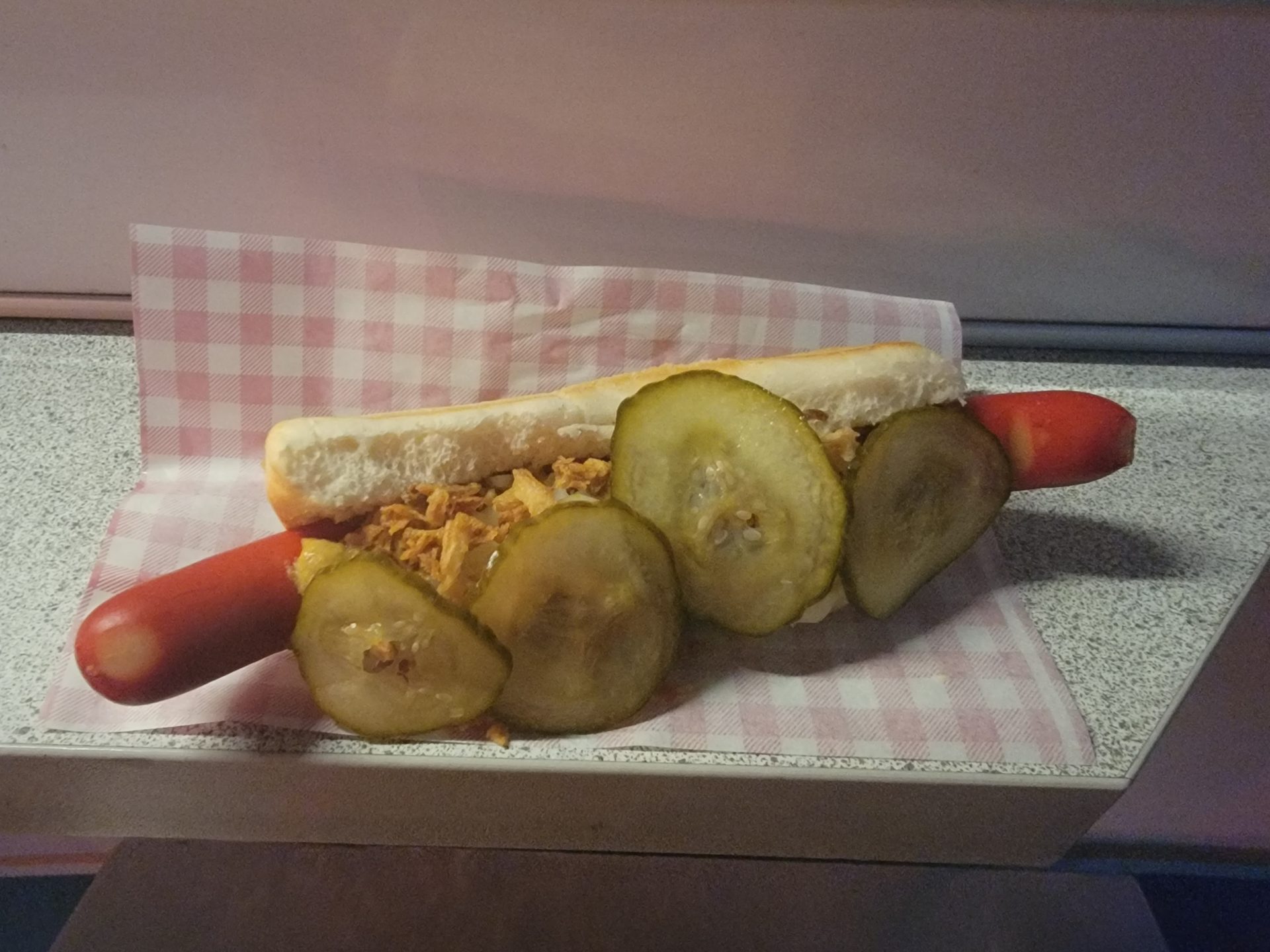 a hot dog with pickles and a bun