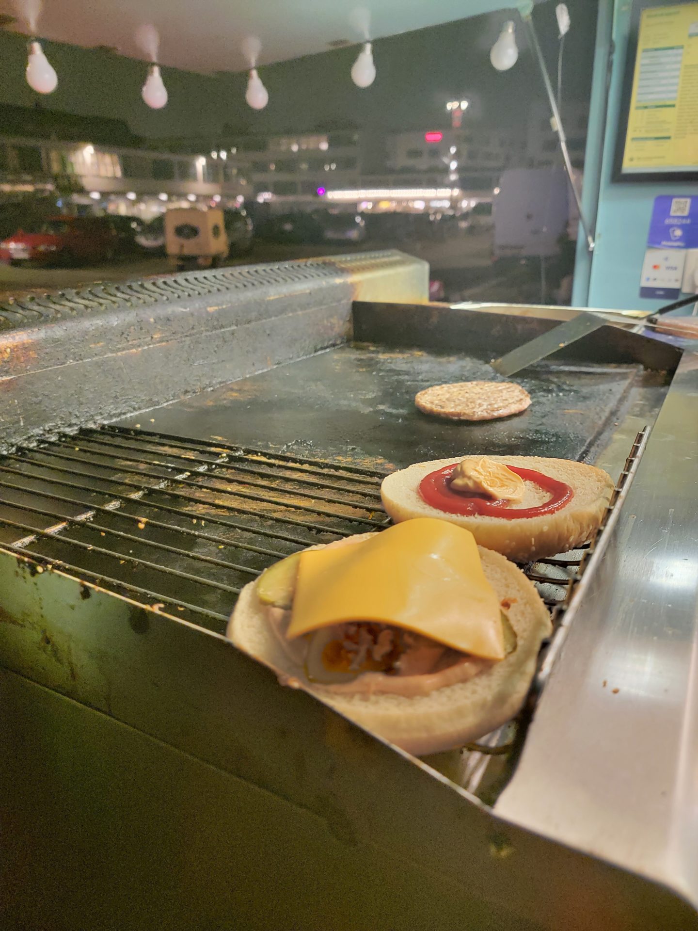 burgers on a grill with a sign in the background
