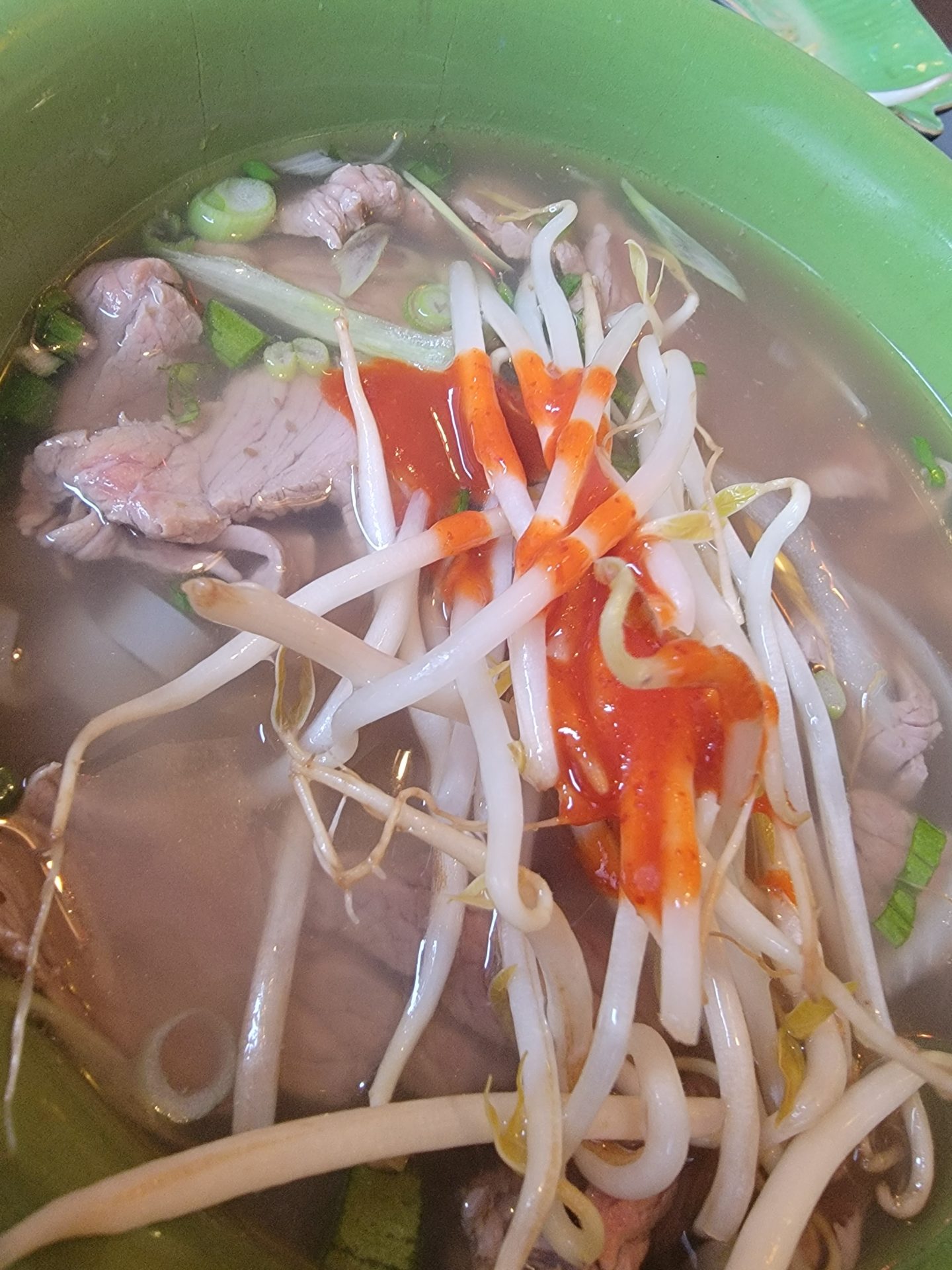 a bowl of soup with meat and sprouts