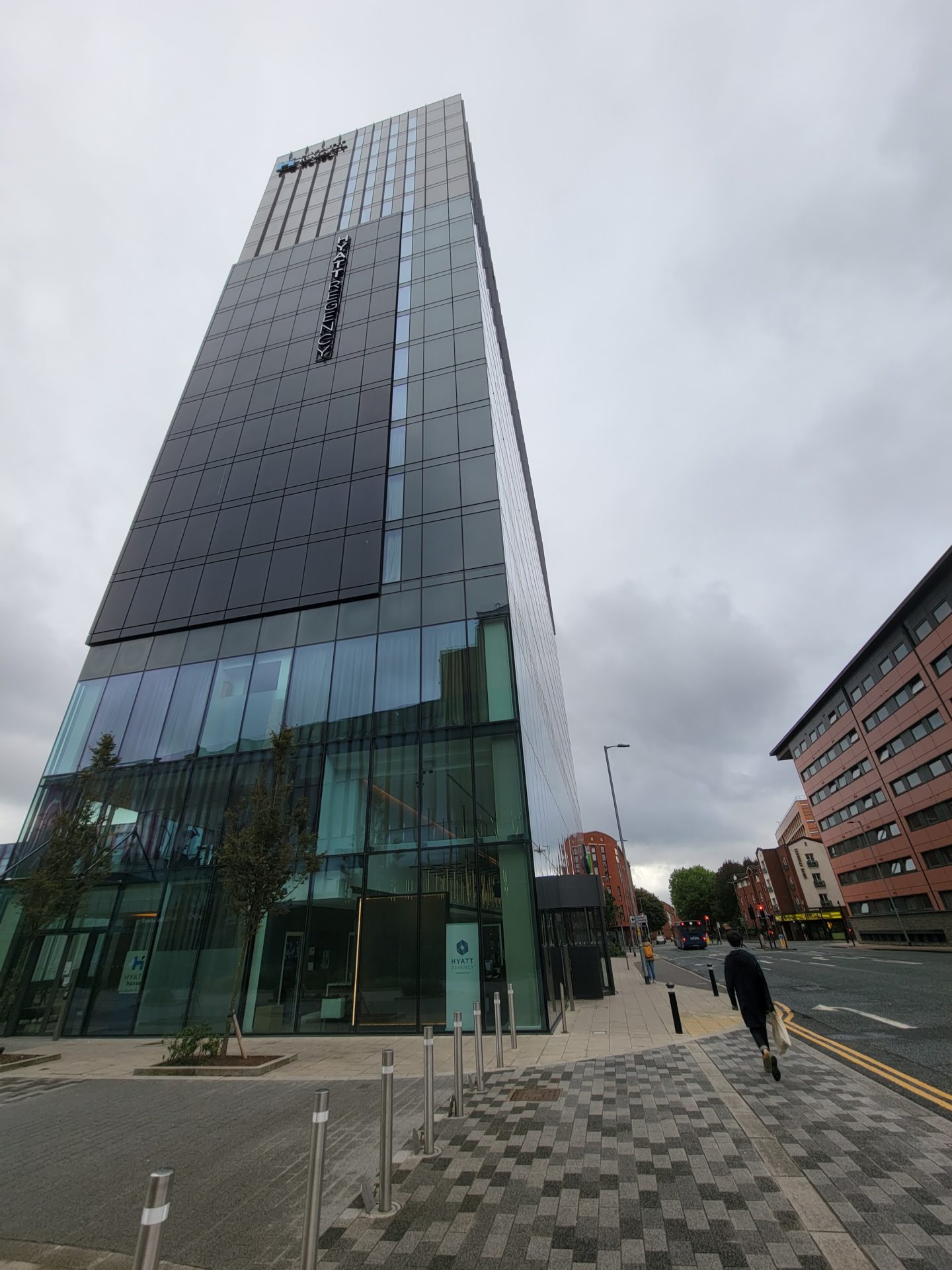 a tall glass building with a person walking on the street