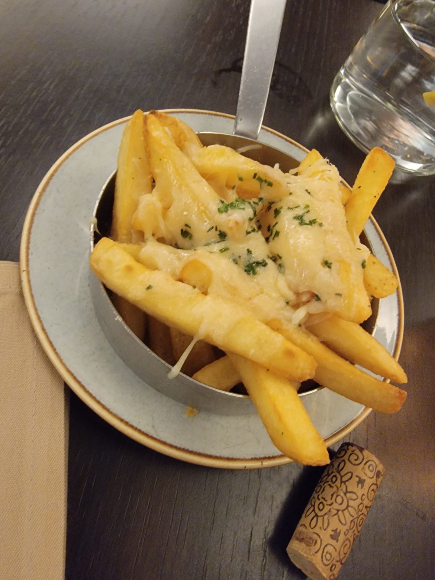 a bowl of french fries with cheese and herbs