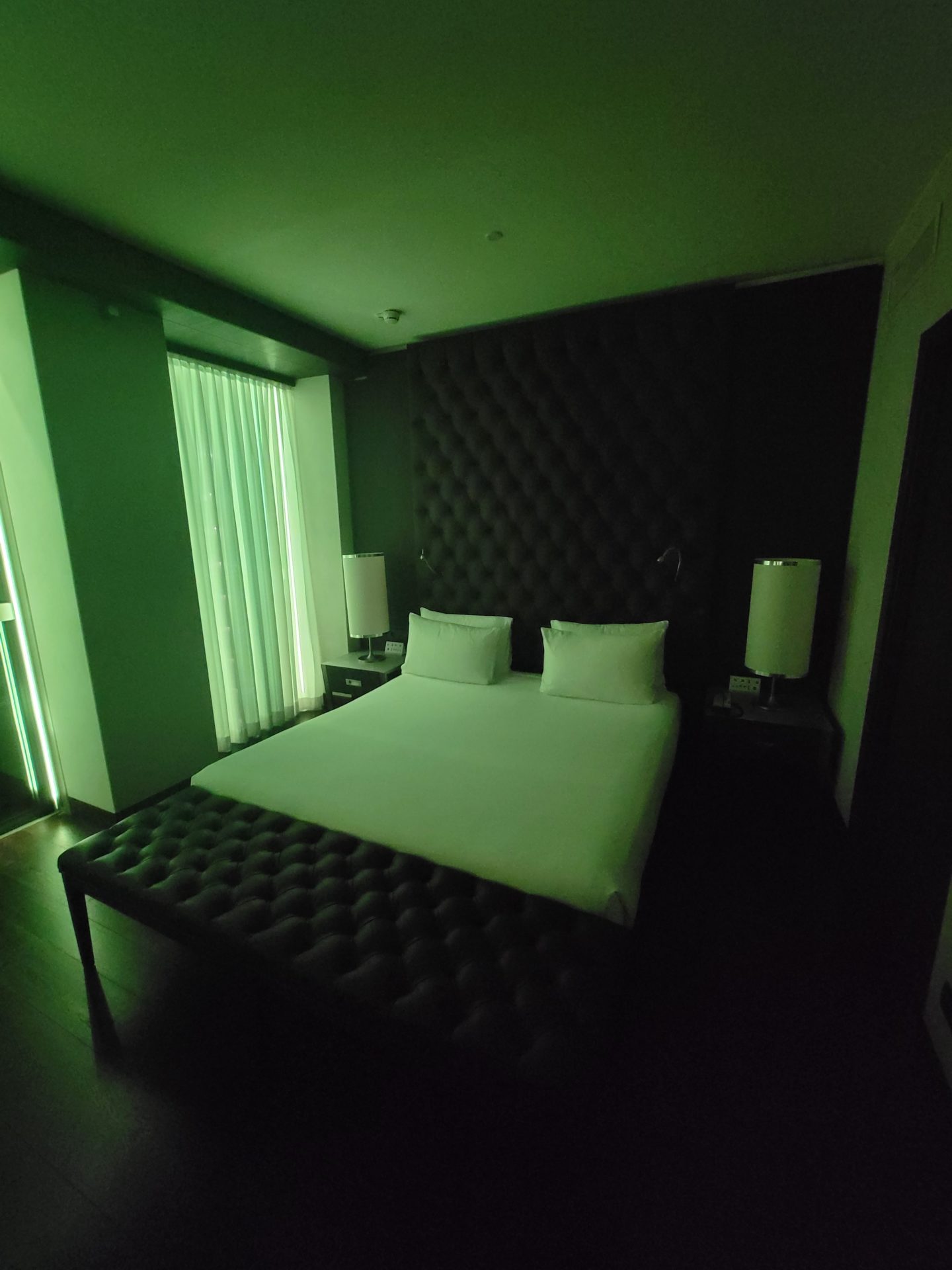 a bed with white pillows and a black bed with green lights