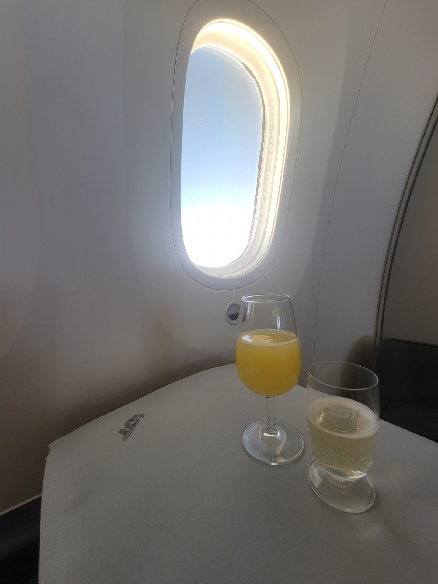 a glass of orange juice and a drink on a table in an airplane