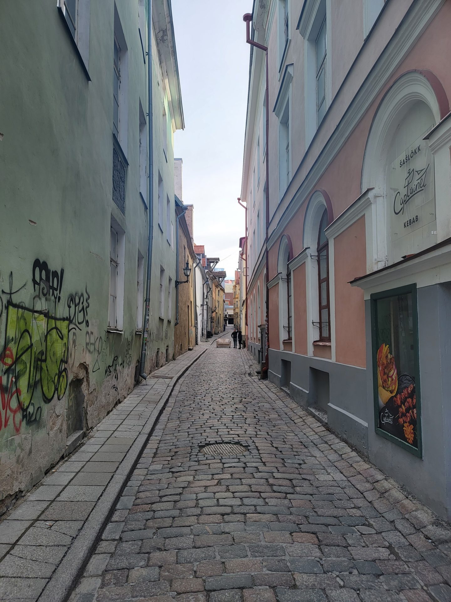 a stone alleyway with buildings and graffiti