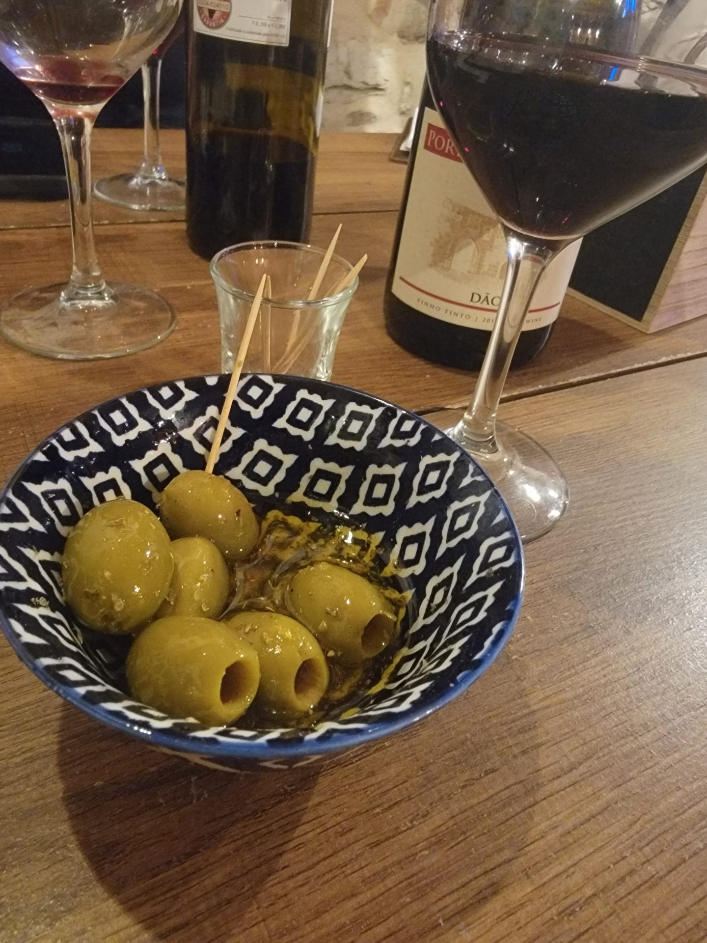 a bowl of green olives and a glass of wine